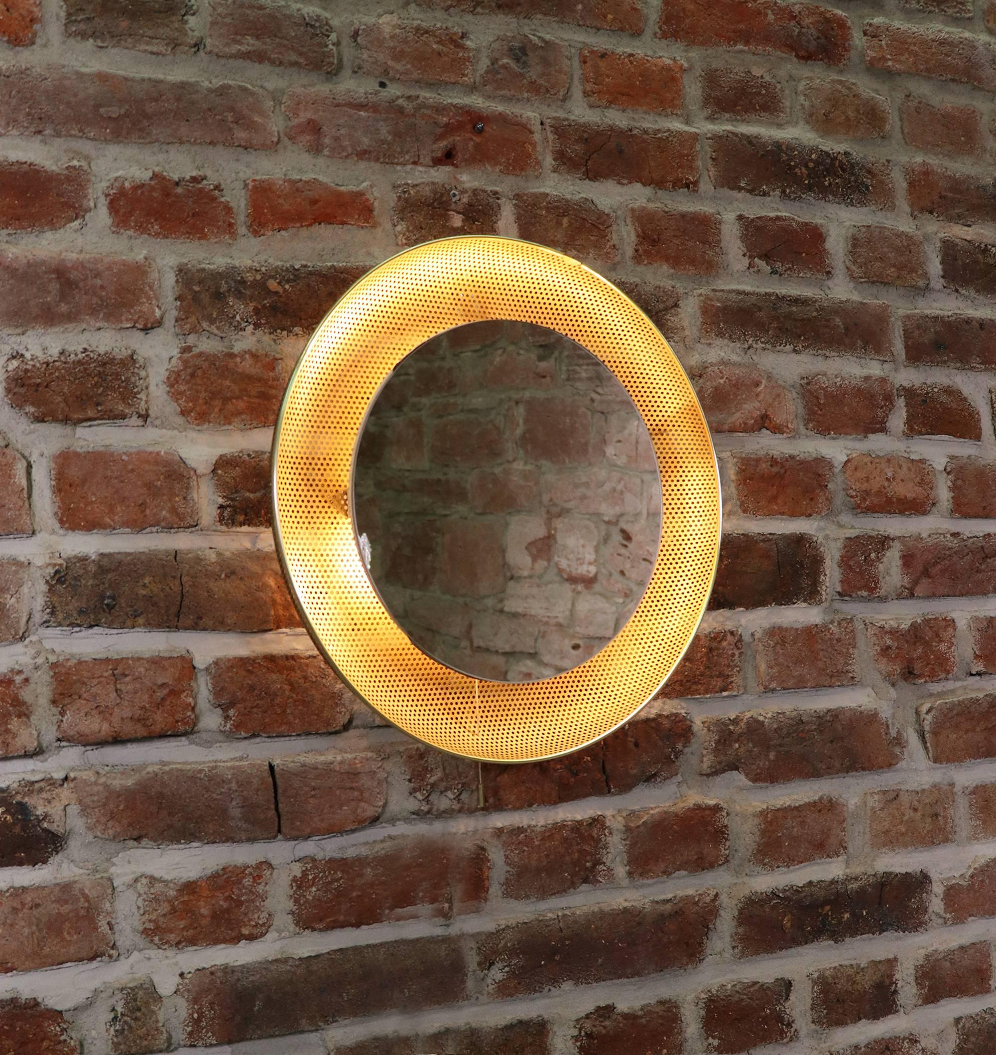 Perforated brass backlight wall mirror with pull string on/off switch.
Attributed to Mathieu Matégot for Artimeta, Netherlands. 
The mirror takes three small Edison bulbs.