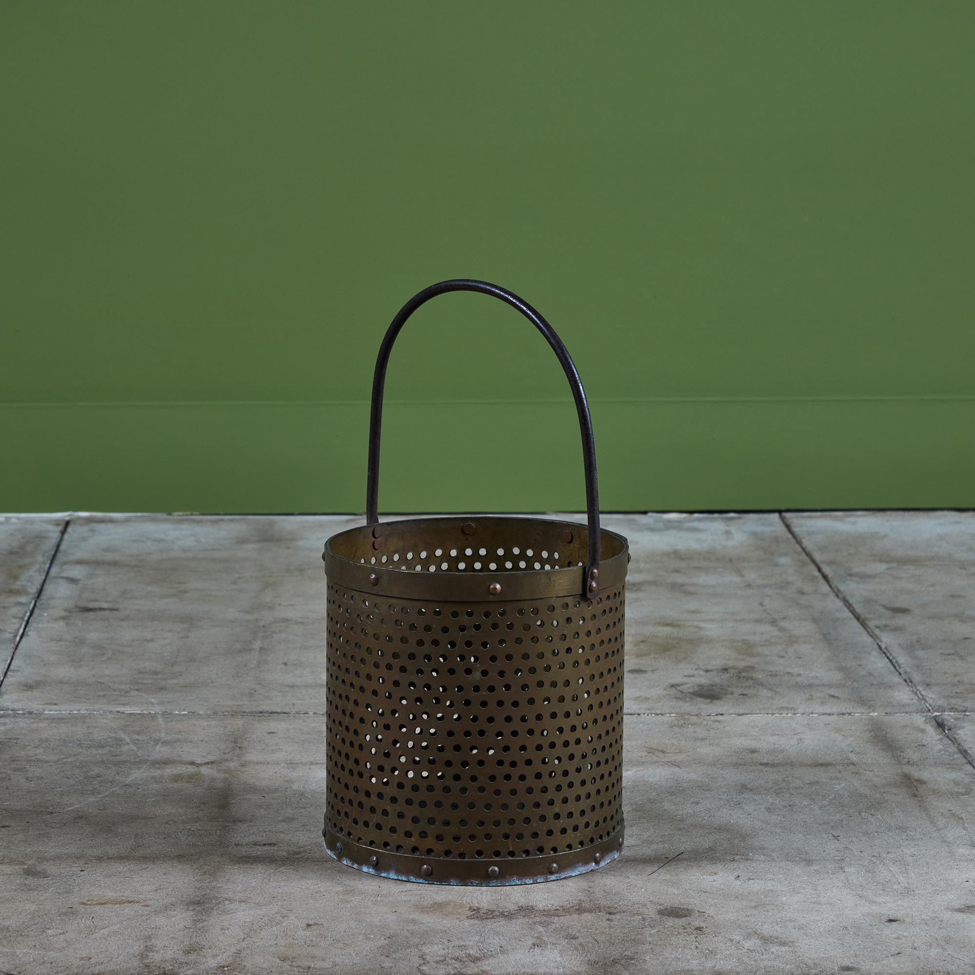 Brass pail with curved handle. This piece features a round perforated body with rivets at both the top and bottom of the pail. It would be a great décor piece or waste basket.

Dimensions
10.5