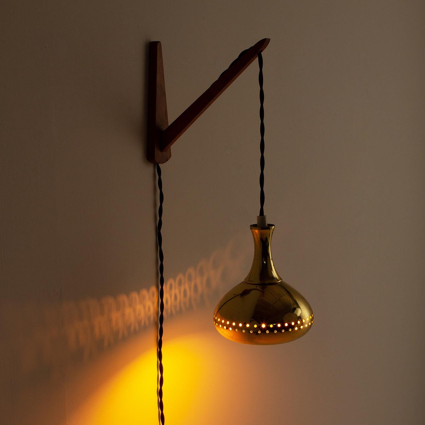 A perforated brass pendant with scratch-made wooden wall hanging bracket. Signs of age and patina on the brass. Designed by Hans-Agne Jakobssen for Hans-Agne Jakobsson AB in Markaryd, Sweden, 1950s. Rewired and PAT Tested.

