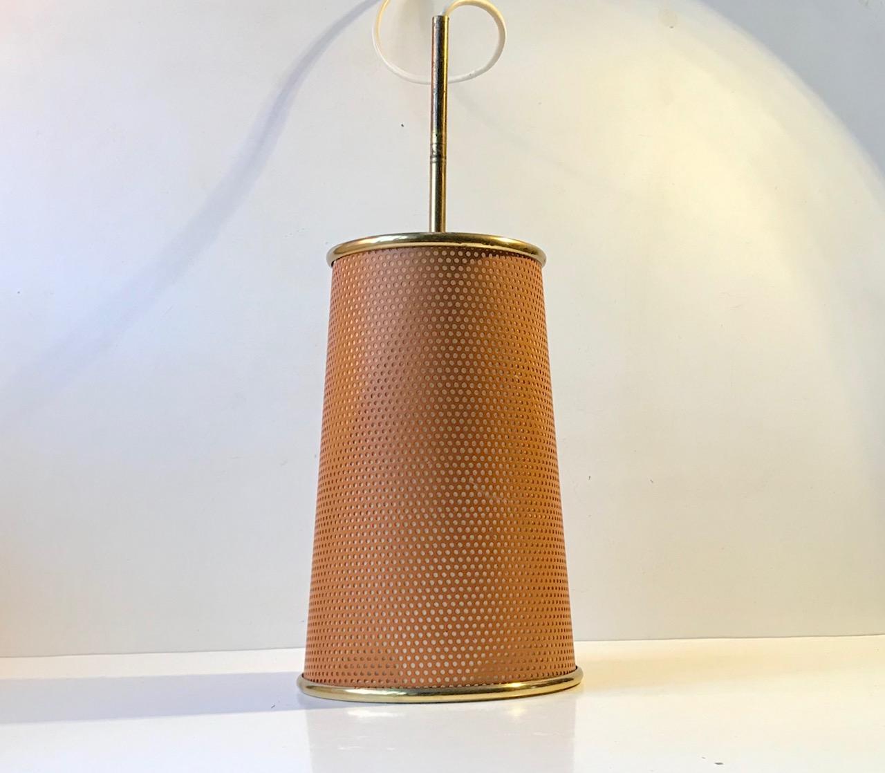 Probably made by either Stilux of Milan or Artemide this unusual cylindrical pendant light features a piercet steel outer shade, a Lucite inner shade and brass edges and top. This combination creates a cosy and warm light that are suitable for most