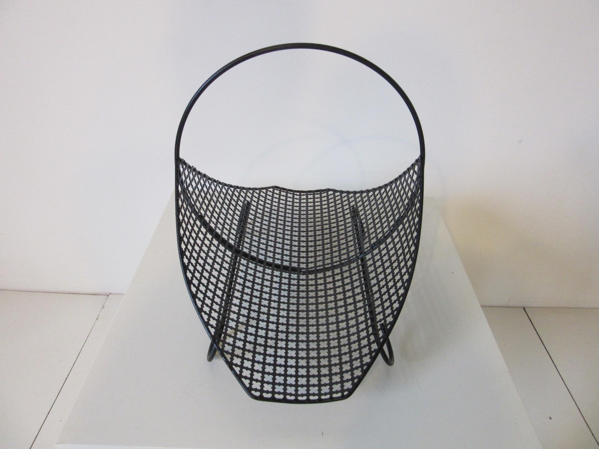 A satin black perforated metal magazine rack or log holder with circle handle and feet in the style of Mathieu Matégot and Artimeta.