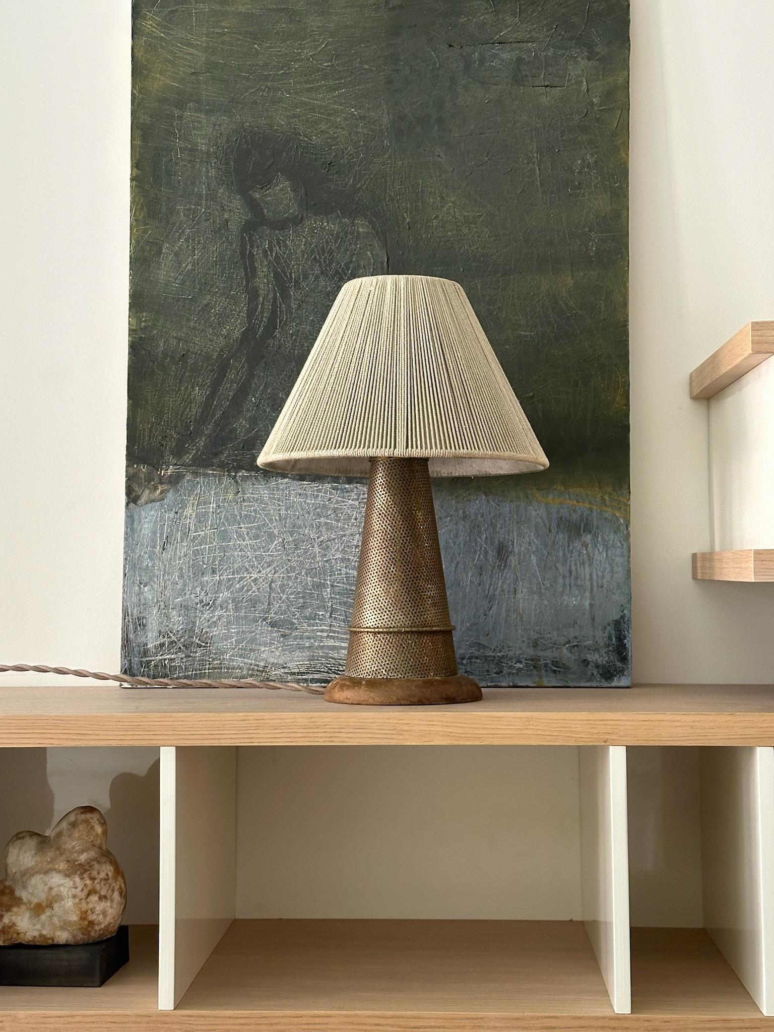 Lampe de table en métal perforé avec une finition cuivre et un abat-jour en cordon enveloppé. Associé à un cordon tressé et enfichable.