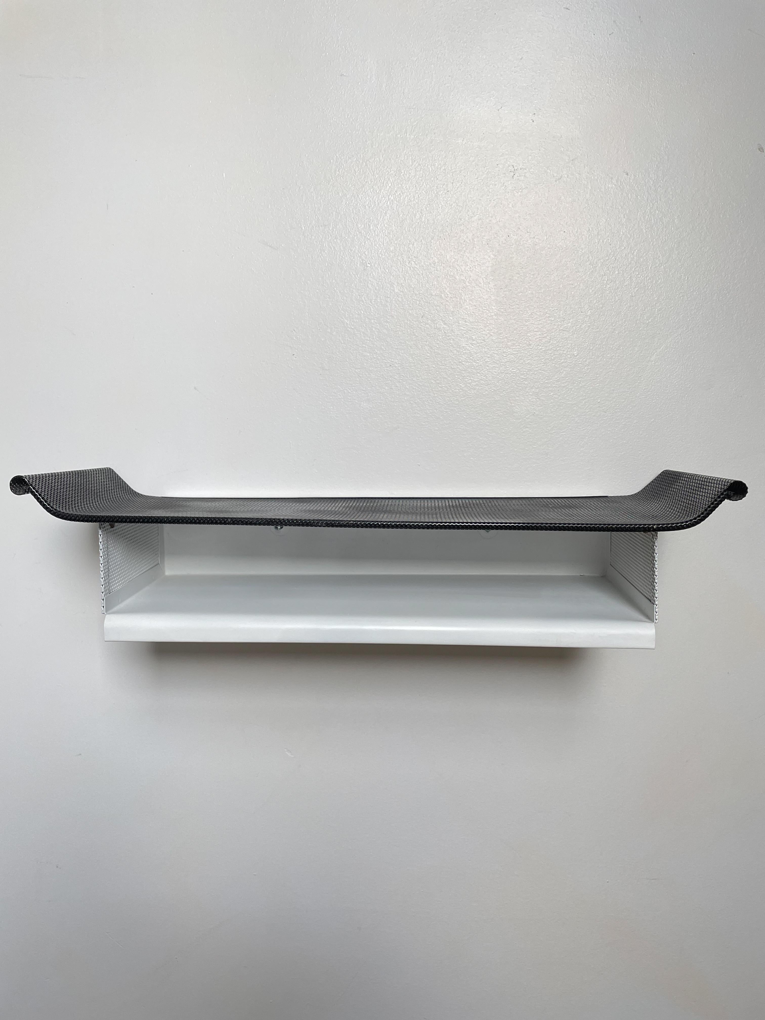 A black and white perforated metal wall shelf by Mathieu Matégot.