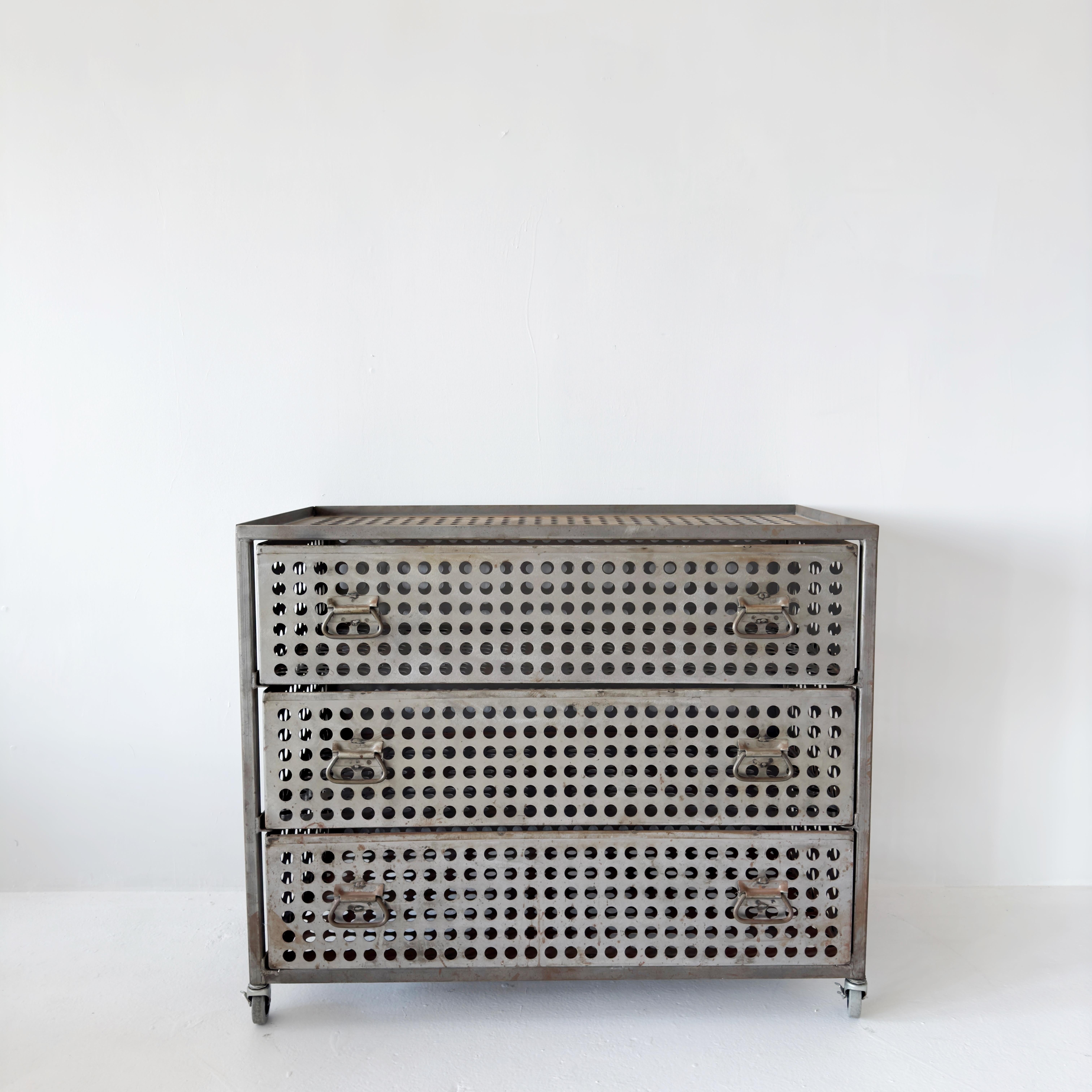 Perforated steel industrial three-drawer dresser on casters. In style of Strawser & Smith early 2000s. Perfect lines and circles, high capacity for weight inside drawers. Steampunk minimalism.

L42.5 D22.5 H35.5

This industrial-style dresser in the