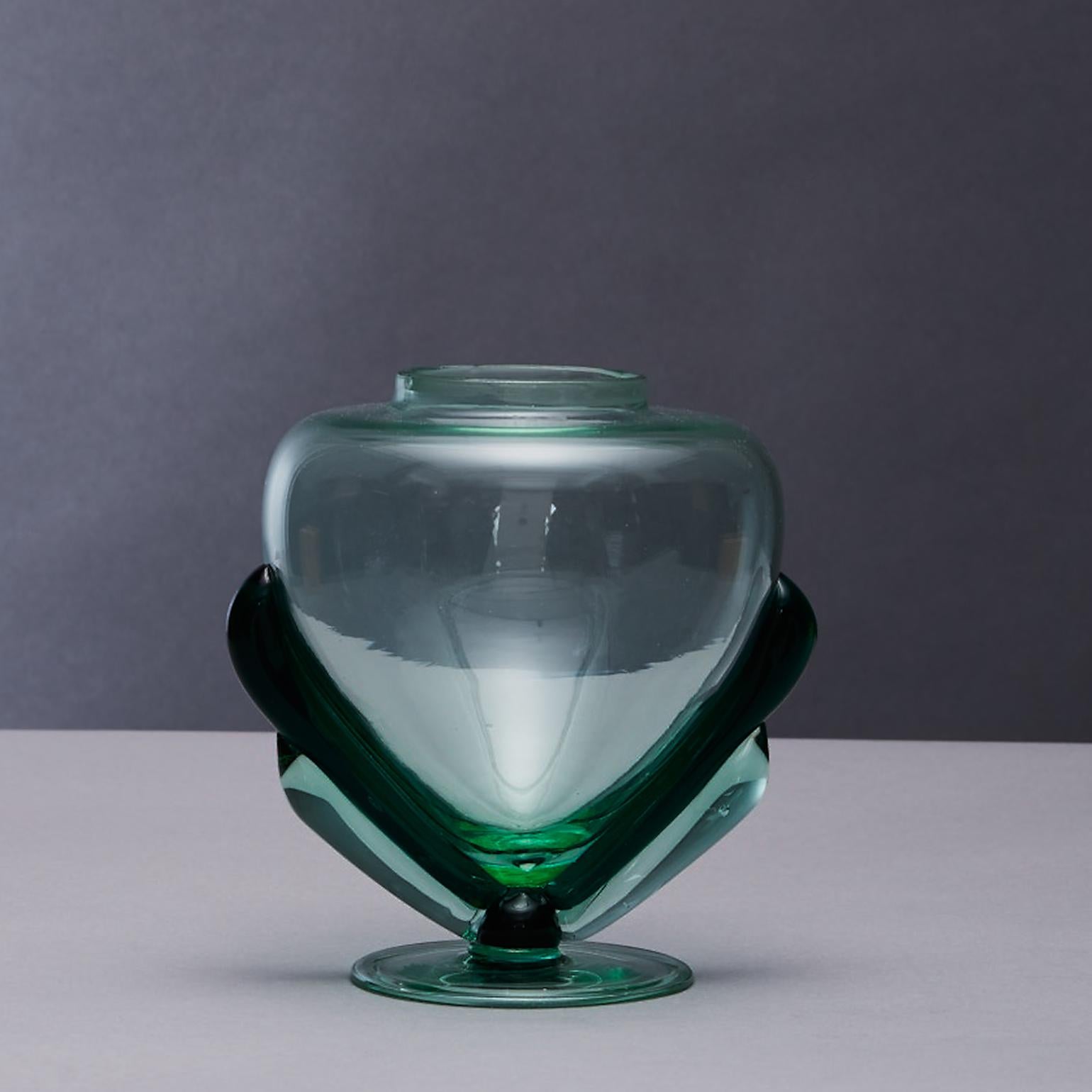 The perfume Bottle by Carlo Scarpa (1906-1978) circa 1928-29 for MVM Cappellin company was formed in 1925 by Paolo Venini and Giacomo Cappellin. The bottle was hand blown into a heart shaped transparent and translucent emerald green glass. There is