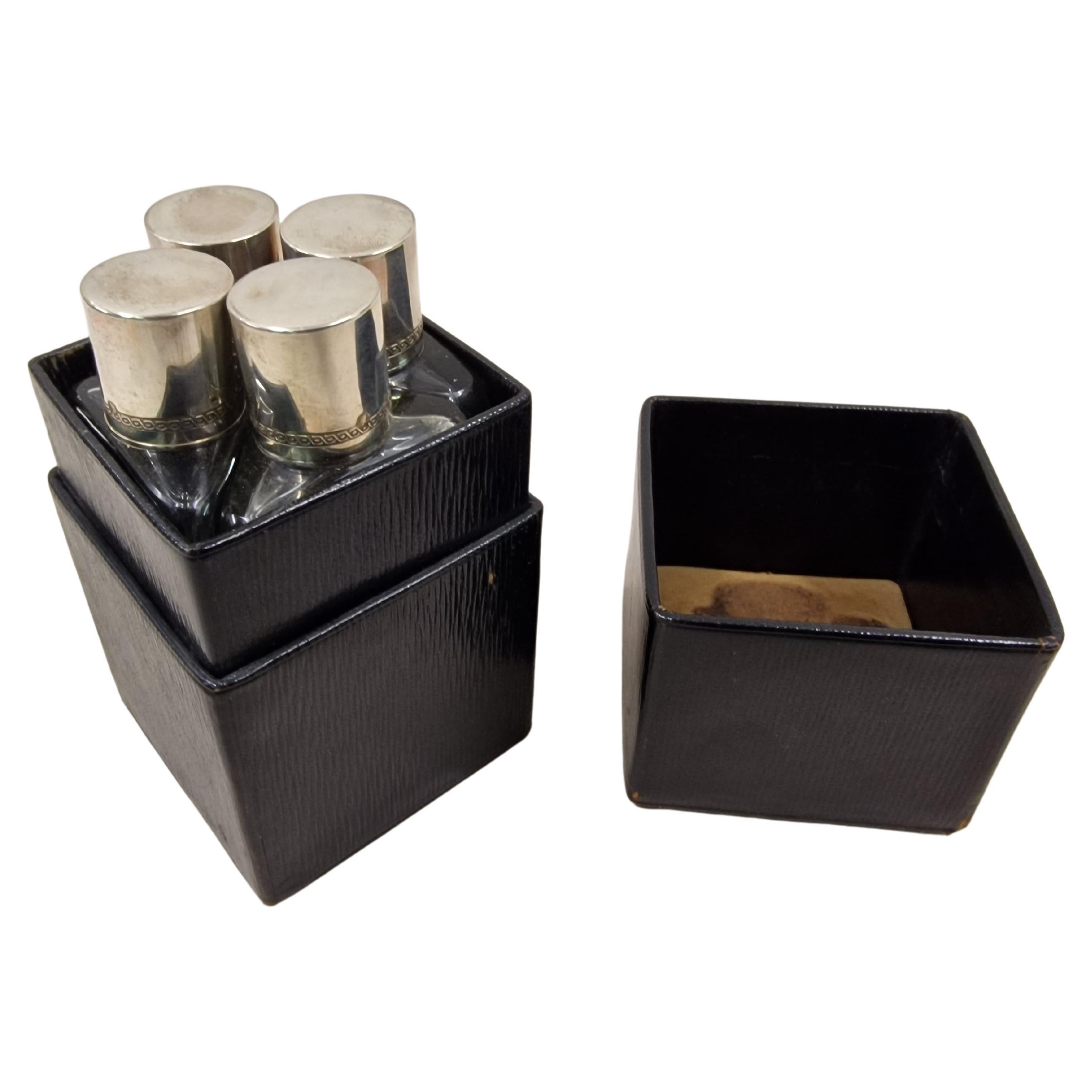 Set of four perfume flacons in the original black leather box, made in the period from 1910 to 1920, in the art nouveau era, most probably made in Austria. 
The lids of the four bottles are out of silver with hallmark and beautifully decorated with