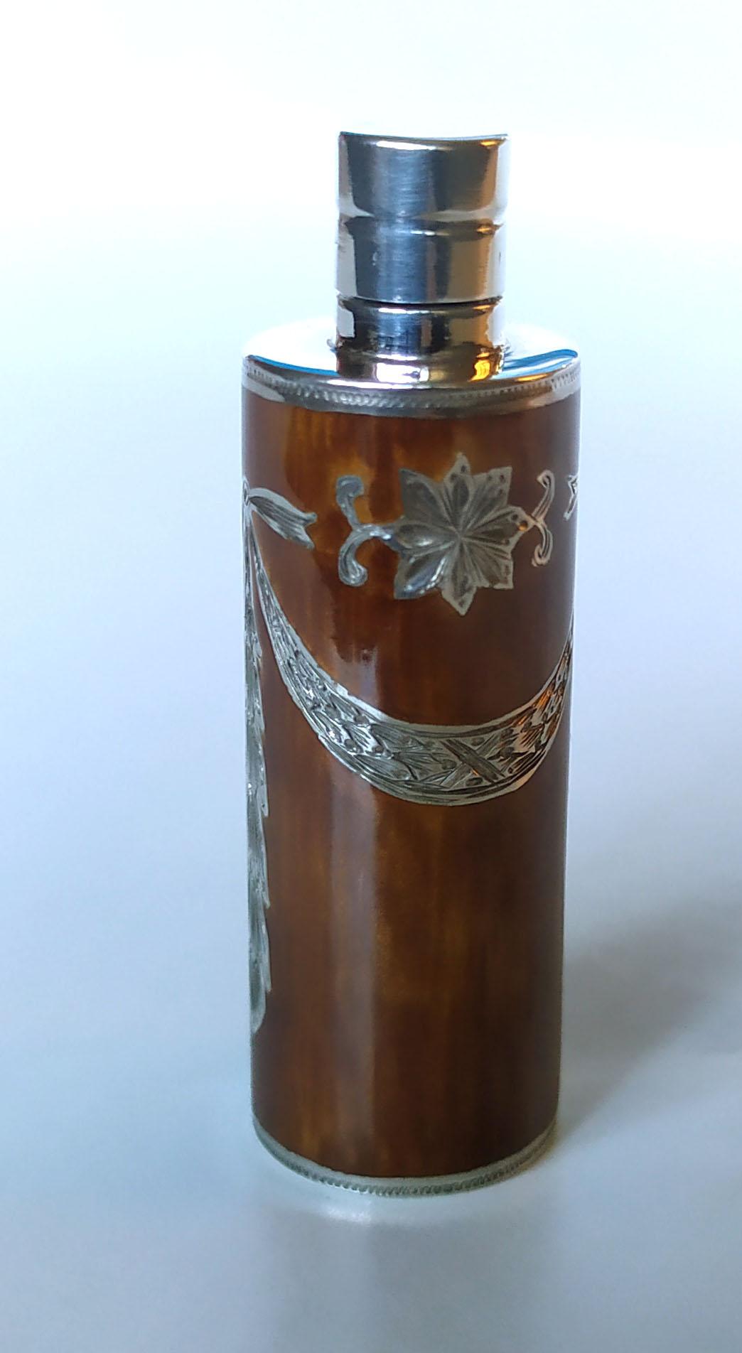 Prova l'epitome del lusso raffinato con questo portaprofumo da borsetta cilindrico, magistralmente realizzato in argento 925/1000 placcato oro. Sormontato da un tappo a vite, presenta squisite incisioni manuali ispirate allo stile Impero di
