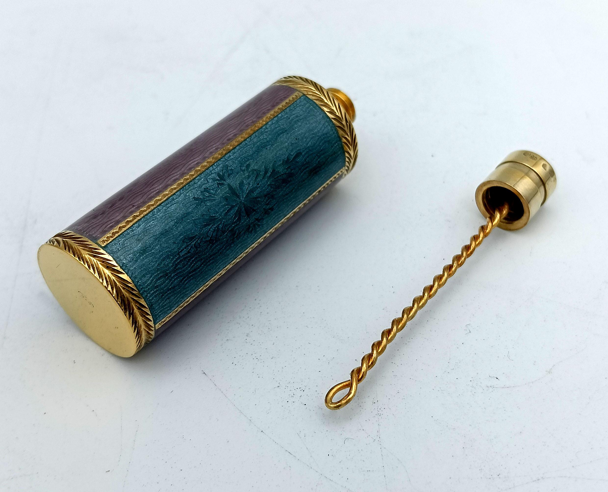 Portaprofumo da borsetta cilindrico in argento 925/1000 placcato oro con tappo a vite e strisce con smalti a fuoco traslucidi bicolore su guilloché e motivi incisi a mano in stile Impero. Diametro 2 cm, altezza totale 6 cm, peso 39 g. Disegnata da