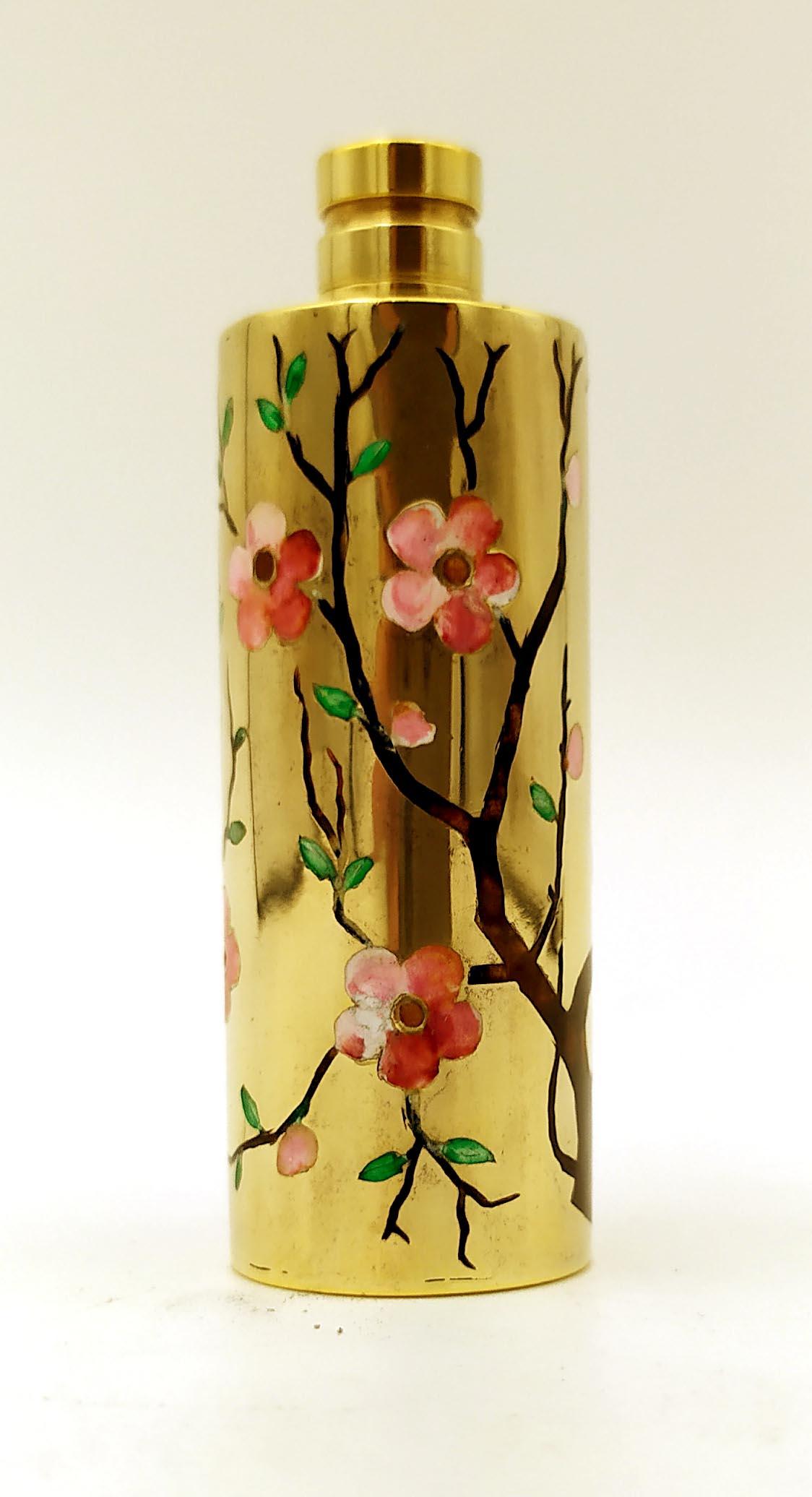 Cylindrical handbag perfume holder in 925/1000 sterling Silver gold plated with screwed cap and fine manual engraving of peach blossom shoots, fire enamelled with various colours, in early 20th century Art Nouveau style. Diameter cm. 2 total height
