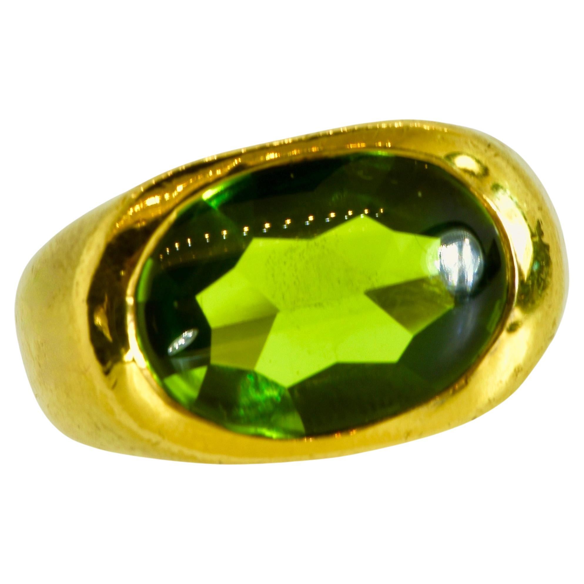 Peridot displaying a pleasing medium lime green - clean without visible inclusions, this oval stone is faceted on the pavillion and a smooth, unfaceted table bezel set flush in the 18K yellow bold and classic vintage ring.  This fine peridot is