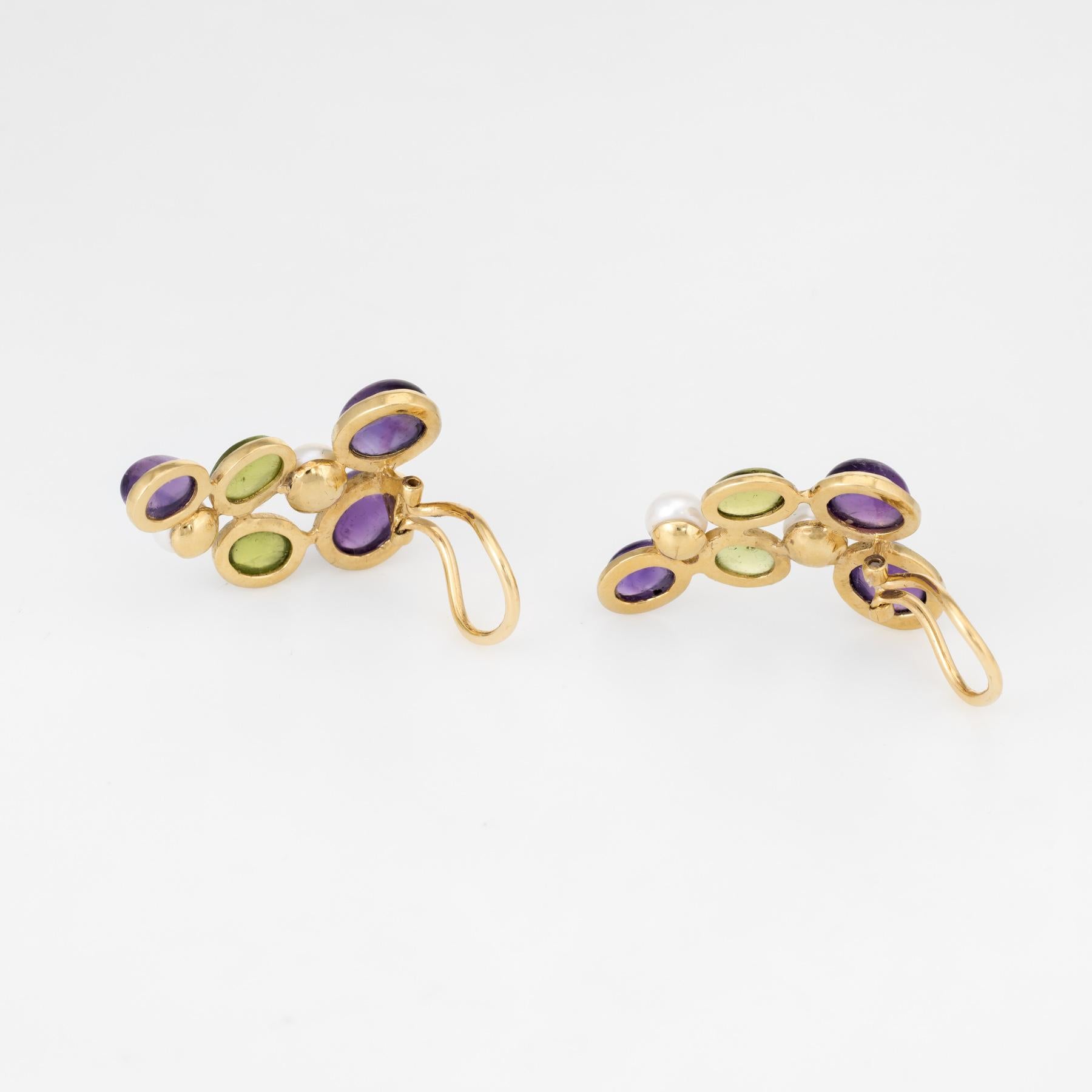 Finely detailed pair of vintage clip earrings, crafted in 18k yellow gold. 

Cabochon cut peridot measures 8mm x 6mm (estimated at 1 carat each - 4 carats total estimated weight), accented with cabochon cut amethyst that measures 9.5mm x 8mm and