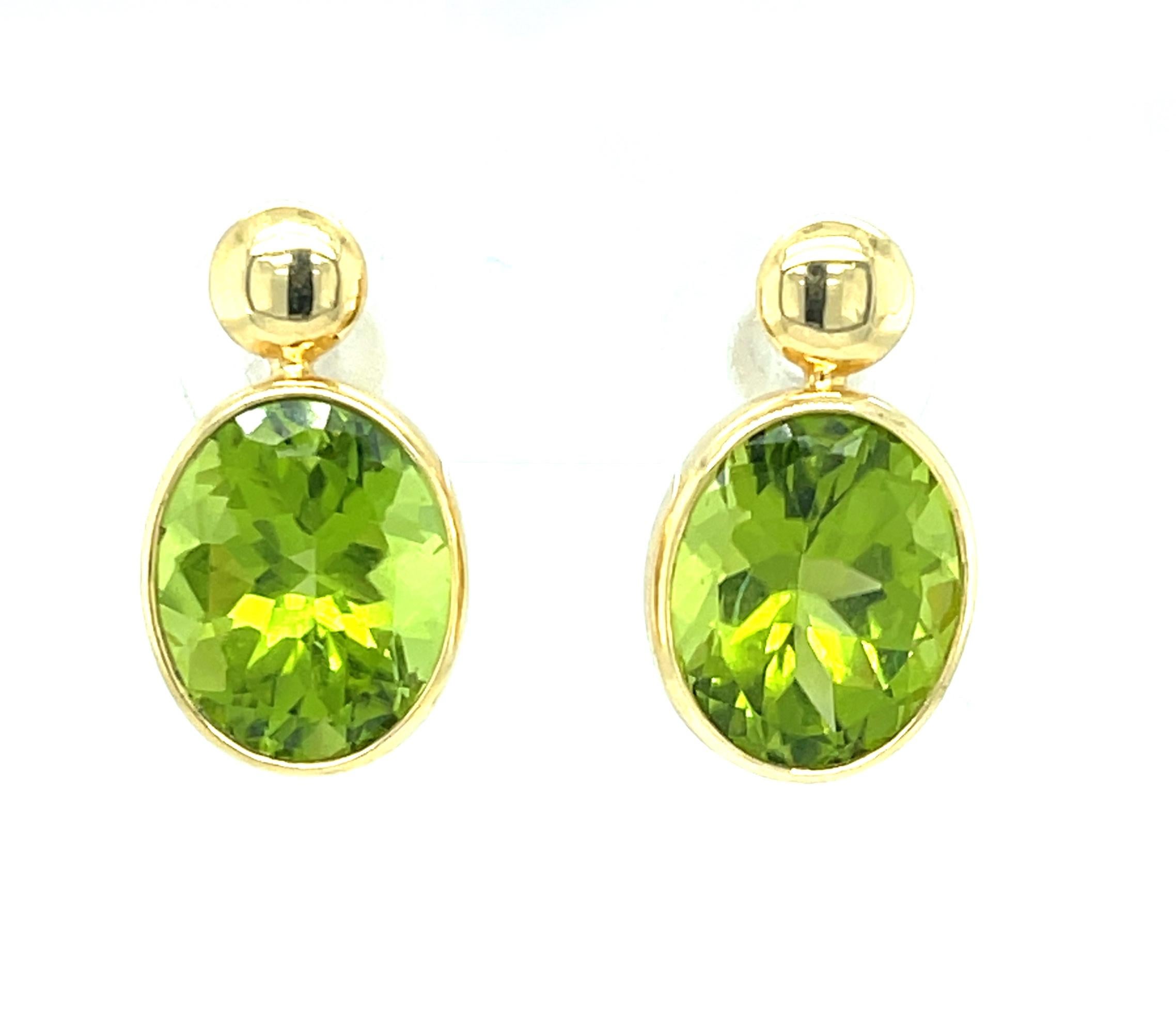 These stylish and versatile 18k yellow gold peridot drop earrings feature a beautifully matched pair of bright, spring green peridots weighing 9.70 carats! The brilliant green gems are set in gorgeous handmade bezels designed to hang just below the