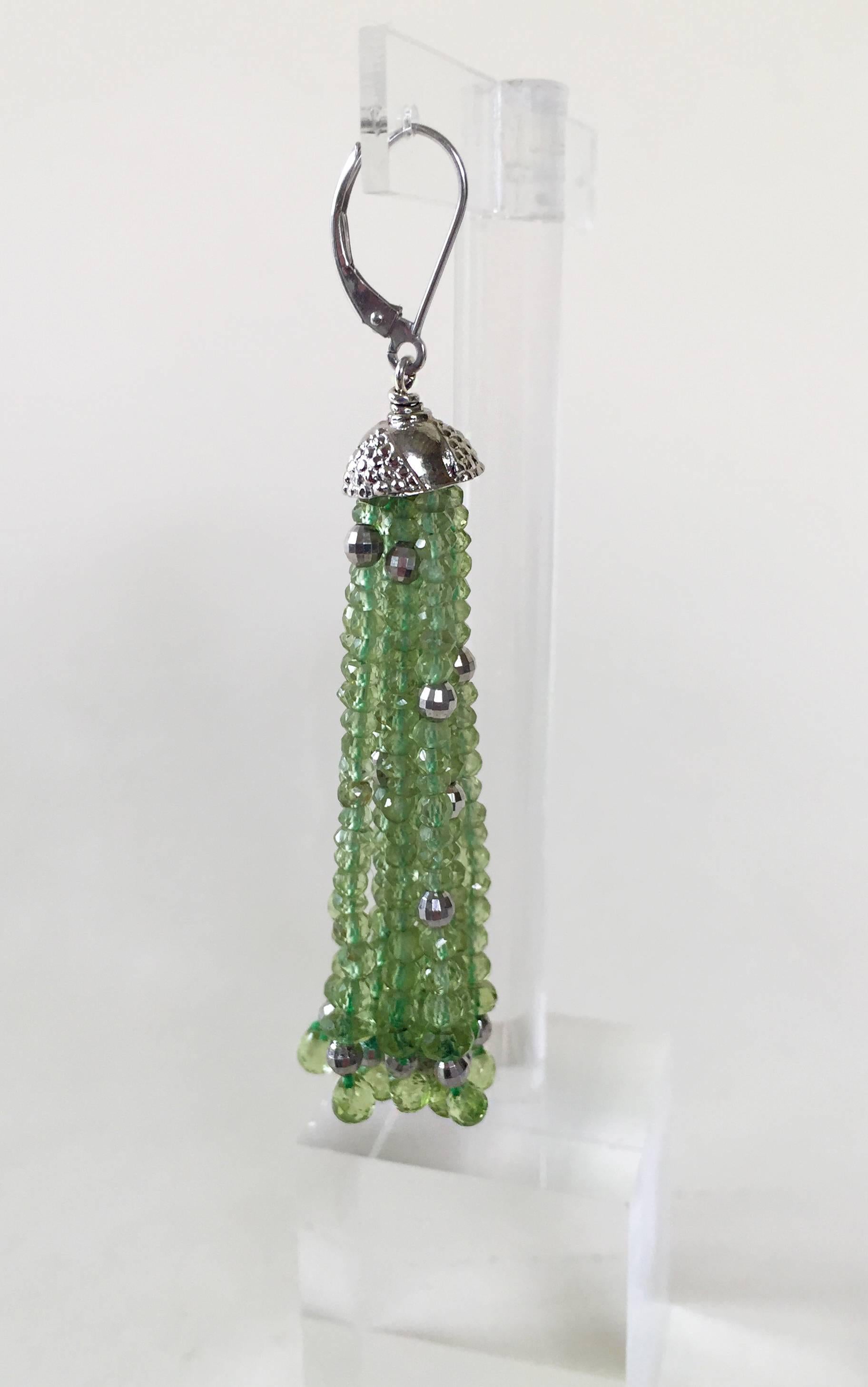 These charming earrings are composed of peridot graduated strands that finish with small peridot briolettes. Accenting the shine of the faceted peridot is white gold plated silver faceted beads and a designed white gold plated silver cup. Completing