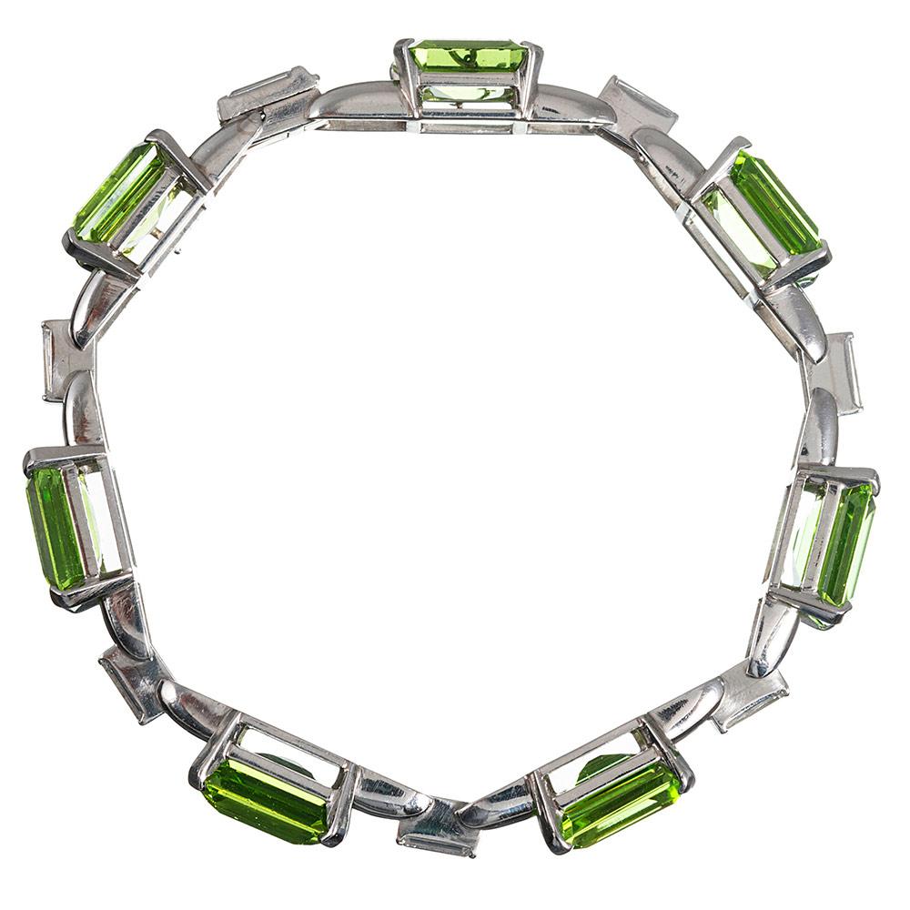 Classically designed and beautifully styled, this platinum bracelet contains seven emerald cut peridots and fourteen baguette diamonds. The peridots weigh approximately 50 carats combined and exhibit intense, transparent grassy green color. They are