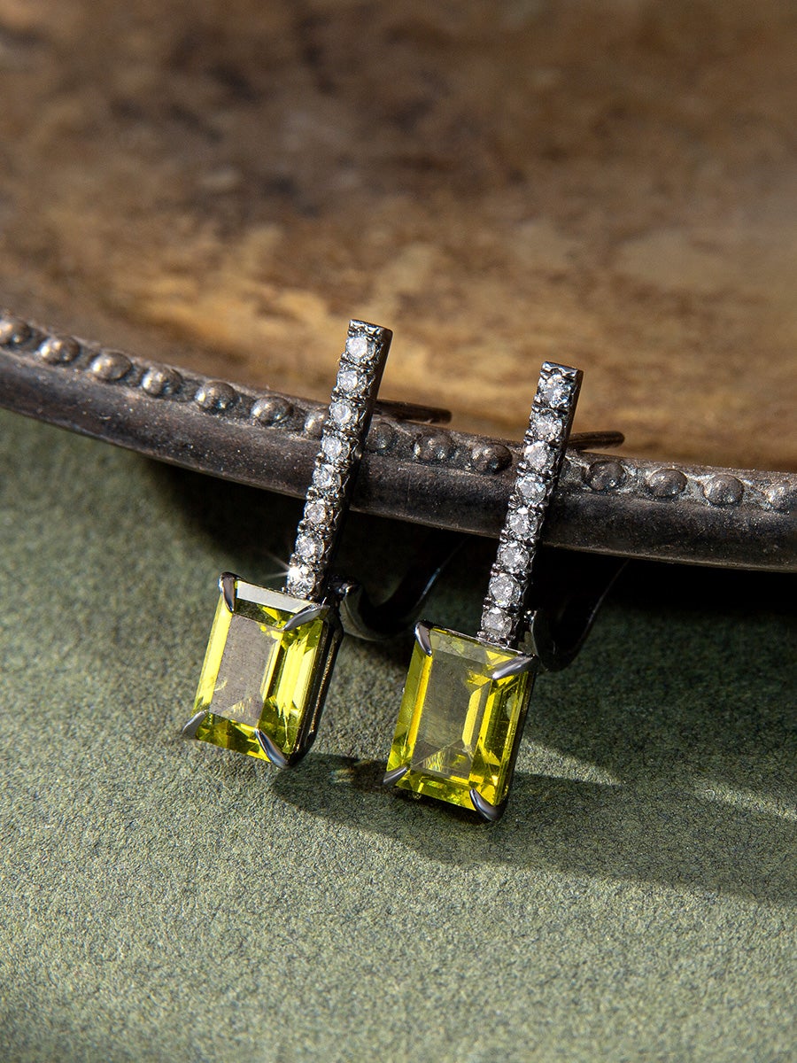 The Peridot Diamond Earrings in question boast an exquisite and meticulously crafted design, characterized by their patinated black silver composition. With an understated yet captivating unisex style, these earrings offer a newfound sense of