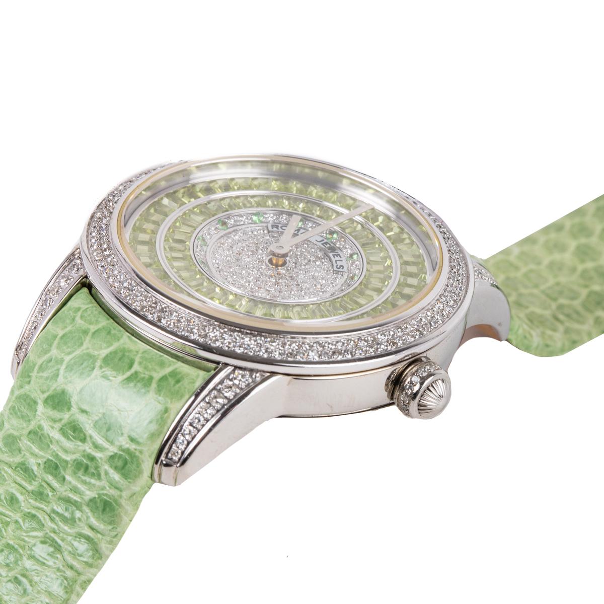 This watch features peridot and diamond stones on the face of the watch. The peridot stones have been baguette-cut and the diamonds are round cut.  This watch features automatic movement and is made with stainless steel and fine leather strap.