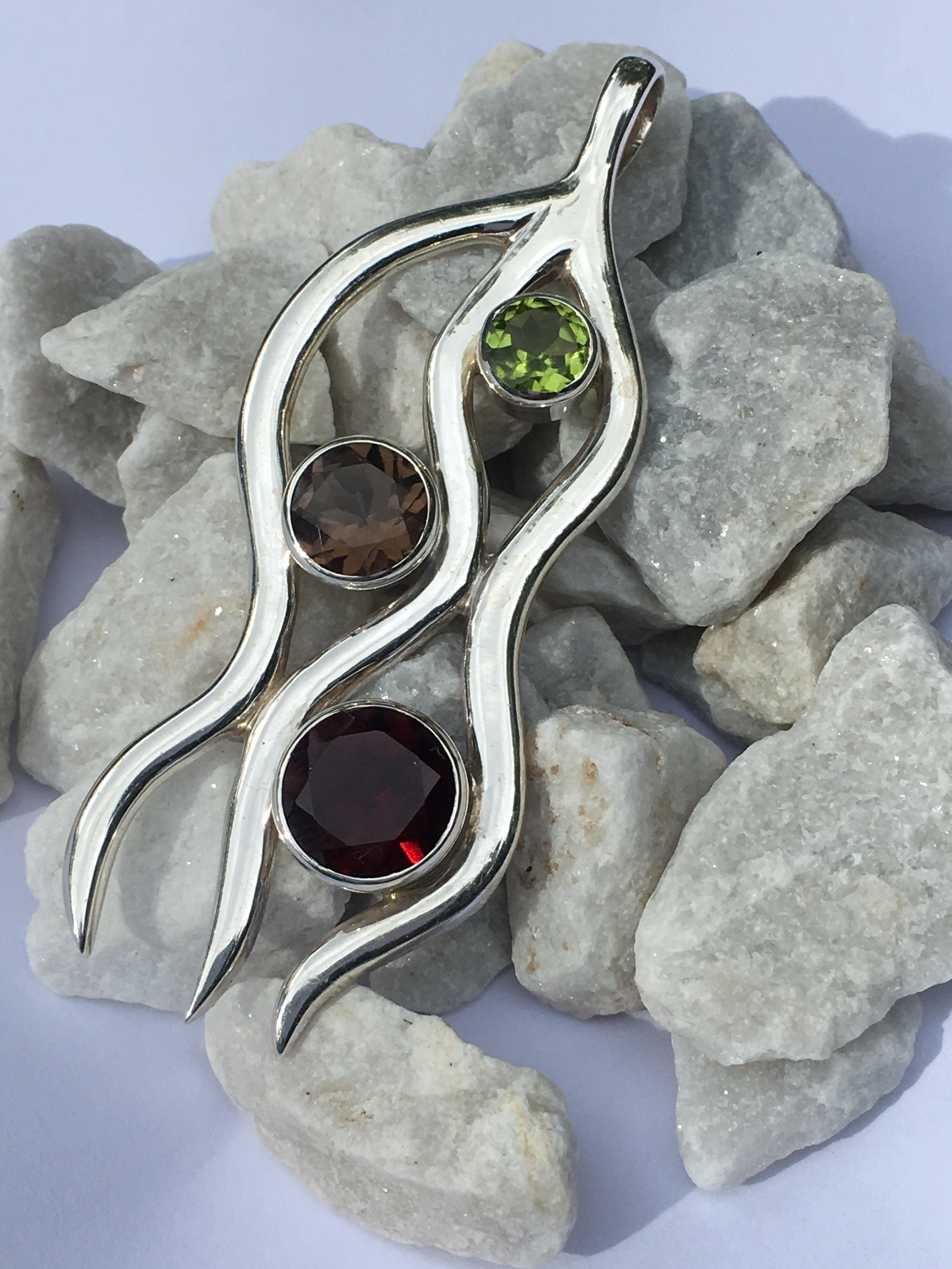 Handmade one of a kind semi precious stones pendant is set in sterling silver. The pendant is 7 MM Peridot, 9MM Smokey Quartz and 11 MM Garnet, You can use this pendant on silver chain or leather band.


