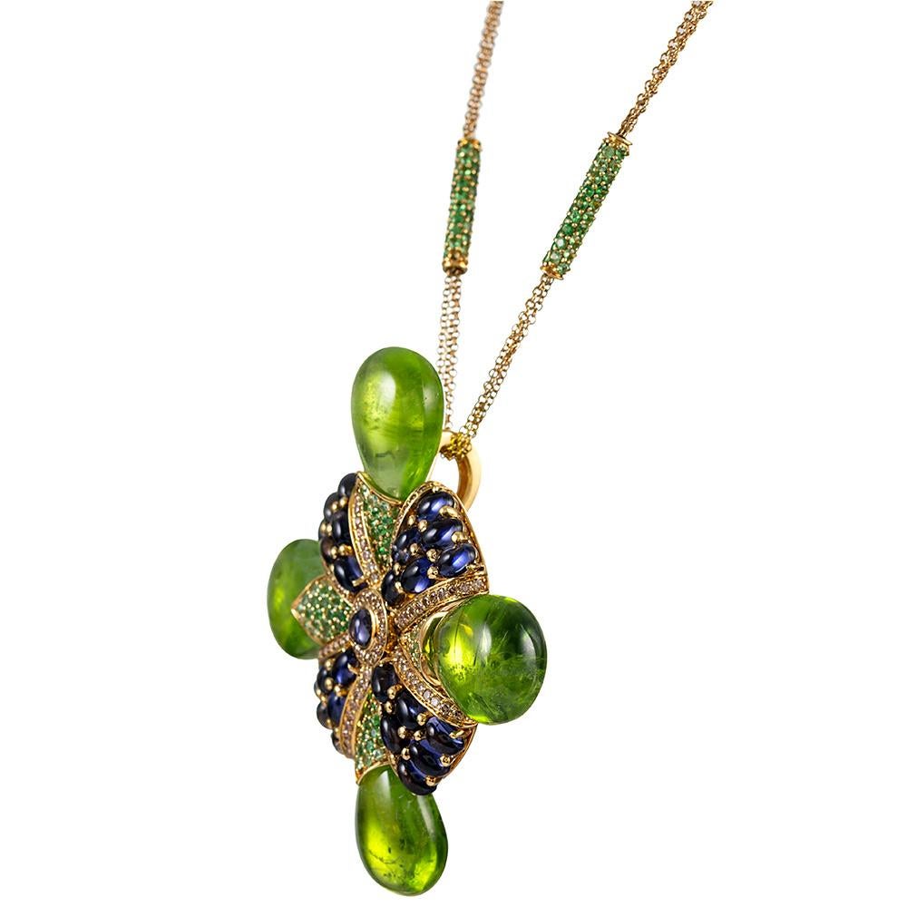 Substantial and alluring, this large Maltese cross is made of iolite cabochons, faceted tsavorite garnets and tipped with large teardrops of peridot at the compass points. The color combination is striking and absolutely gorgeous. Wear this piece