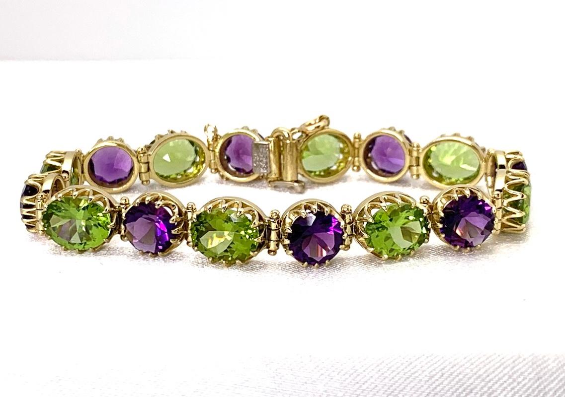 This exquisite 18k yellow gold tennis bracelet features over 33 carats of amethyst and peridot in luscious jewel-toned grape colors! Each round amethyst and oval peridot is showcased in its own gorgeous 18k yellow gold setting that is as beautiful