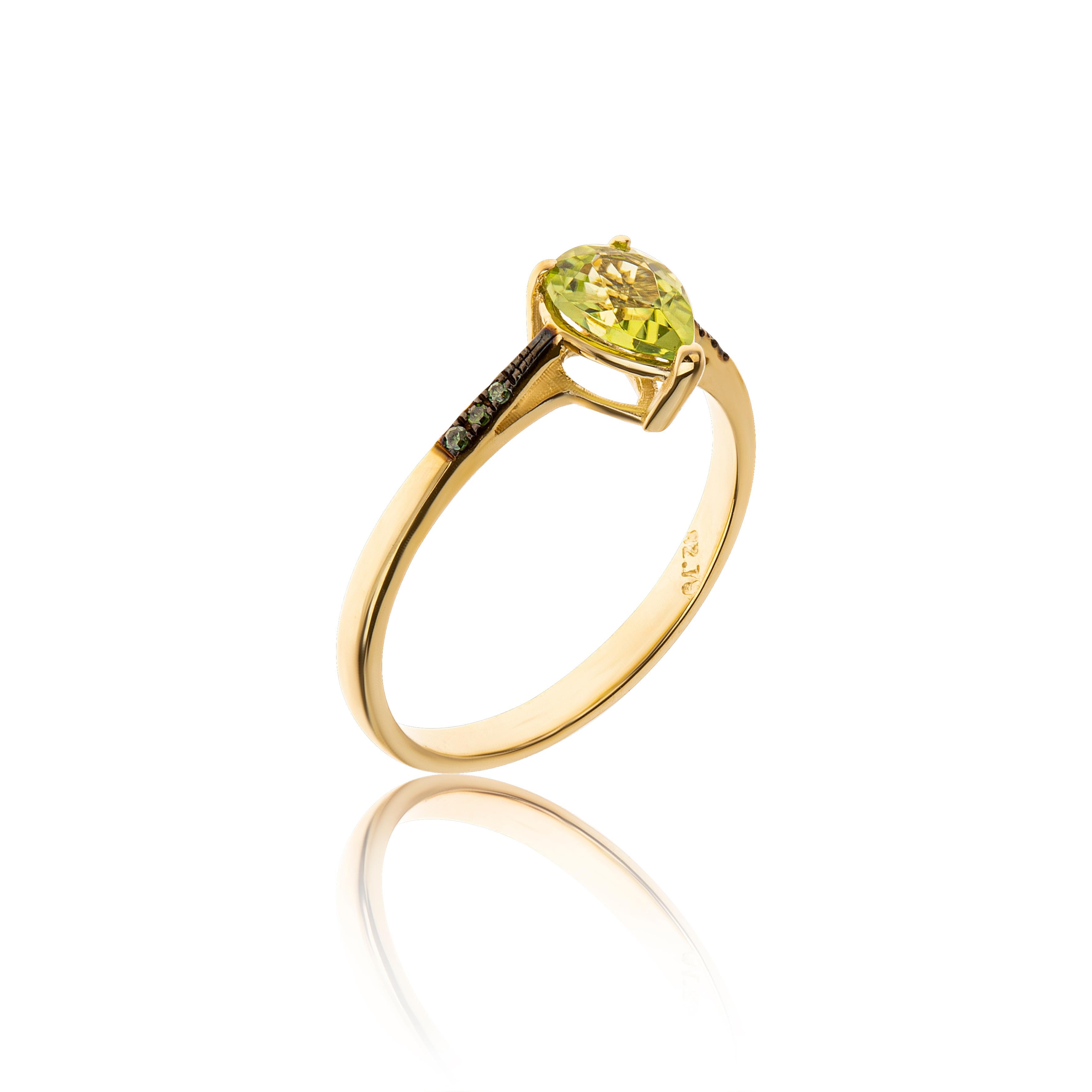 Peridot Pear Cut Ring with Green Diamonds Brilliant Cut Pave Setting in 18Kt Gold.
The central stone is a peridot, which is cut in pear shape. In the sides of the ring, blue diamonds in brilliant cut and in pave setting, give a different style in