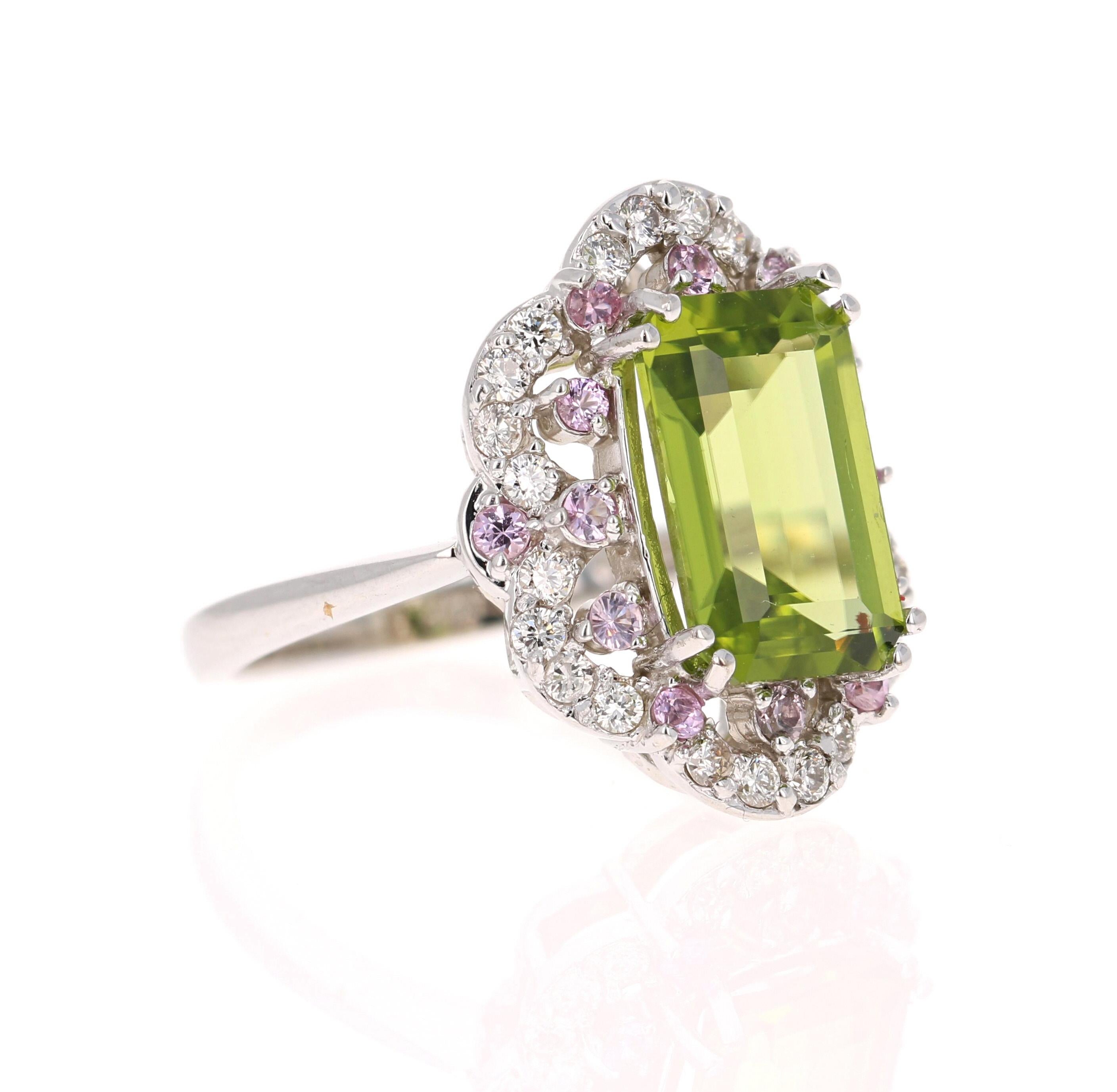 This Peridot and Diamond Ring has a 4.10 Carat Emerald Cut Peridot and is surrounded by 14 Pink Sapphires that weigh 0.33 Carats and 24 Round Cut Diamonds that weigh 0.43 Carats. (Clarity: VS, Color: H) The total carat weight of the ring is 4.86