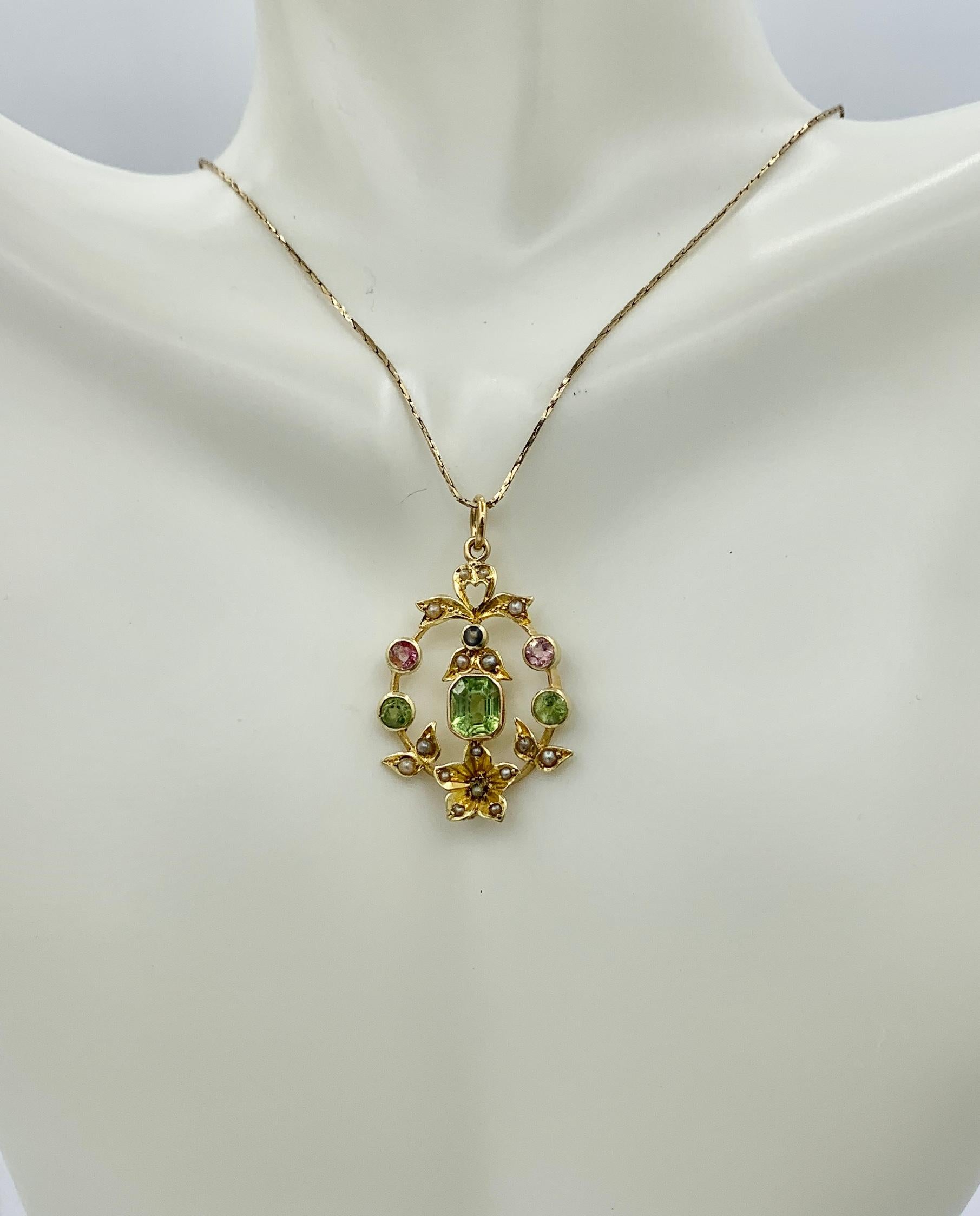 This is a stunning antique Edwardian - Art Deco Peridot and Pink Tourmaline and Pearl Lavaliere Pendant Necklace in 15 Karat Gold.  The gorgeous and full of symbolism jewel has a heart, a forget-me-not flower and a bow motif and the pendant wears