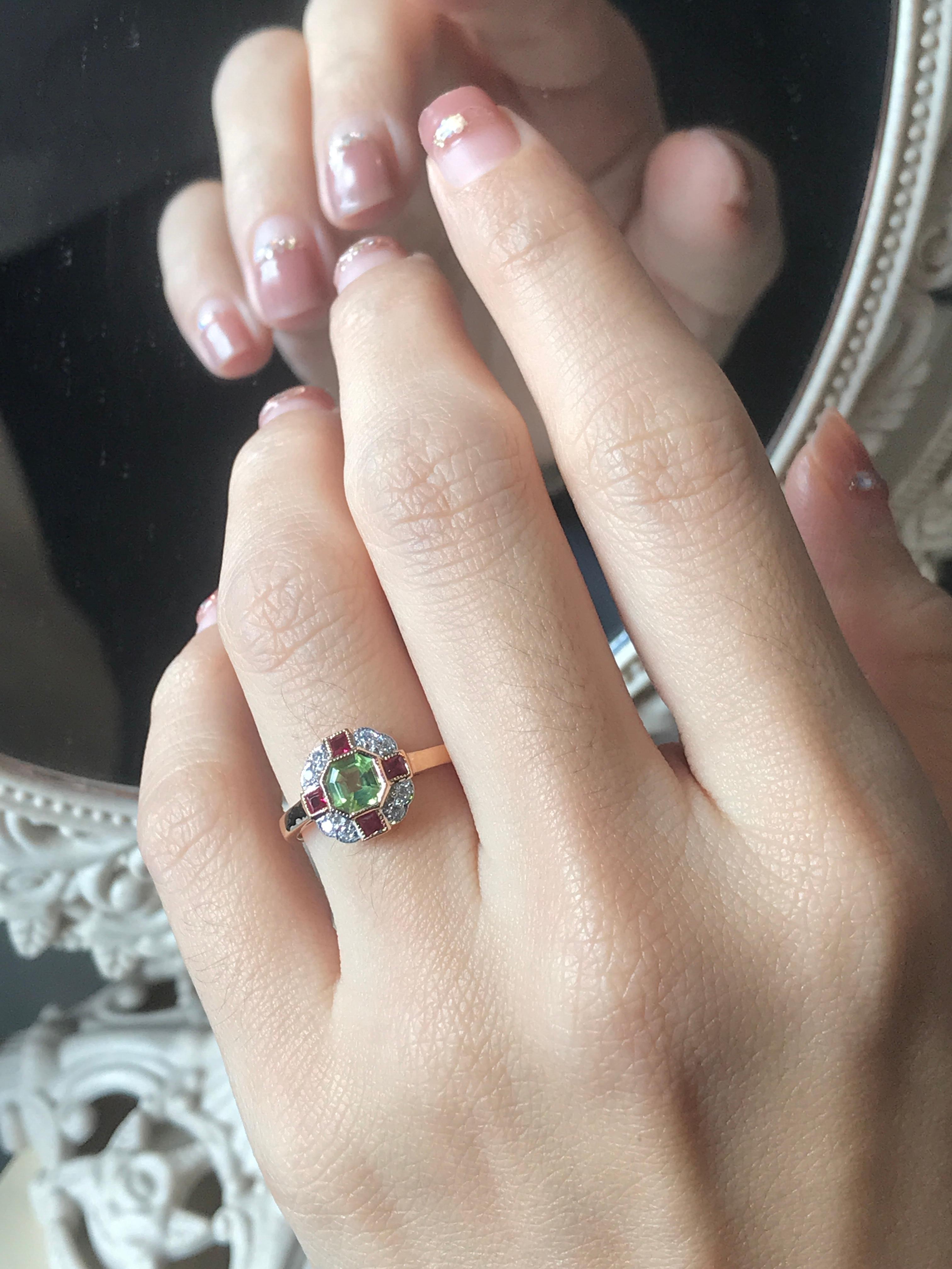 This Peridot, Ruby, and Diamond Art Deco-style Ring radiates vintage glamour with a vibrant twist. A luminous peridot takes center stage, its lively green hue beautifully framed by sparkling diamonds that catch the light from every angle. On each