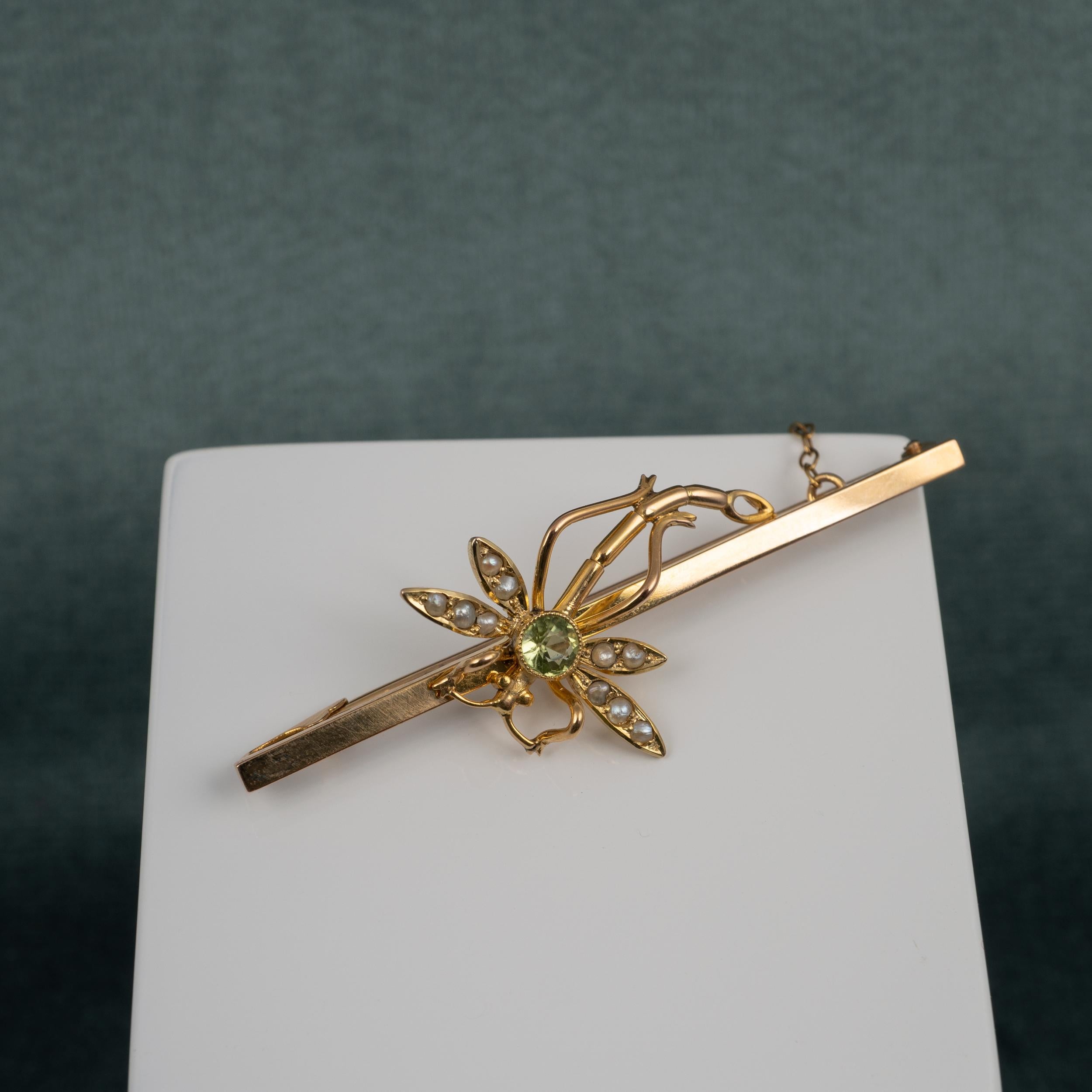 A fine quality antique dragonfly brooch with peridot and pearls crafted in yellow gold and is expertly modeled displaying a gorgeous round-cut peridot and a total of 10 seed pearls set into the doubled wings. 

The stones are lovely in condition and