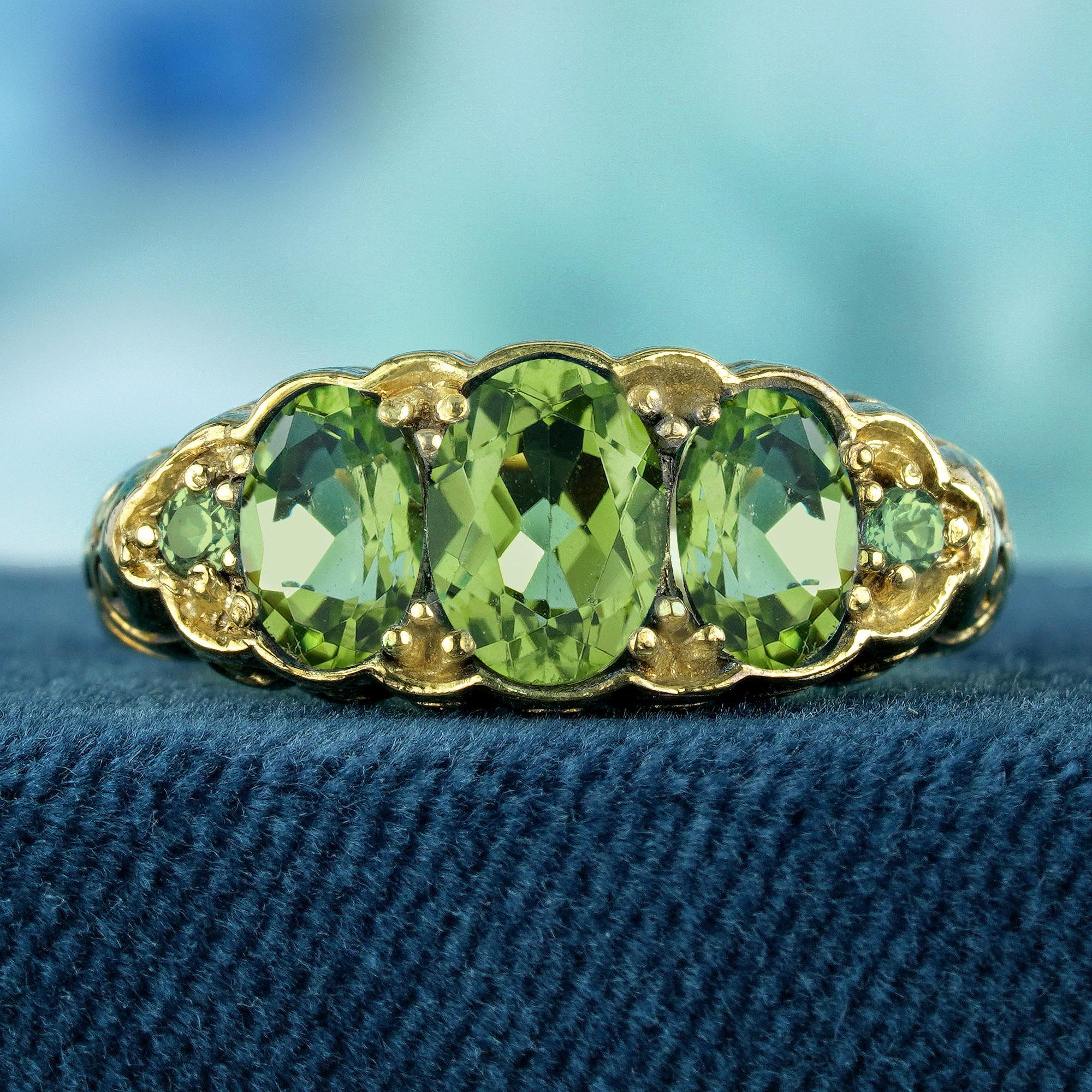 Three beautiful peridots, each carefully set to enhance their vibrant green hues. The stones are arranged in a classic three-stone setting, with intricate vintage-inspired detailing on the band, adding elegance and charm to the design. The