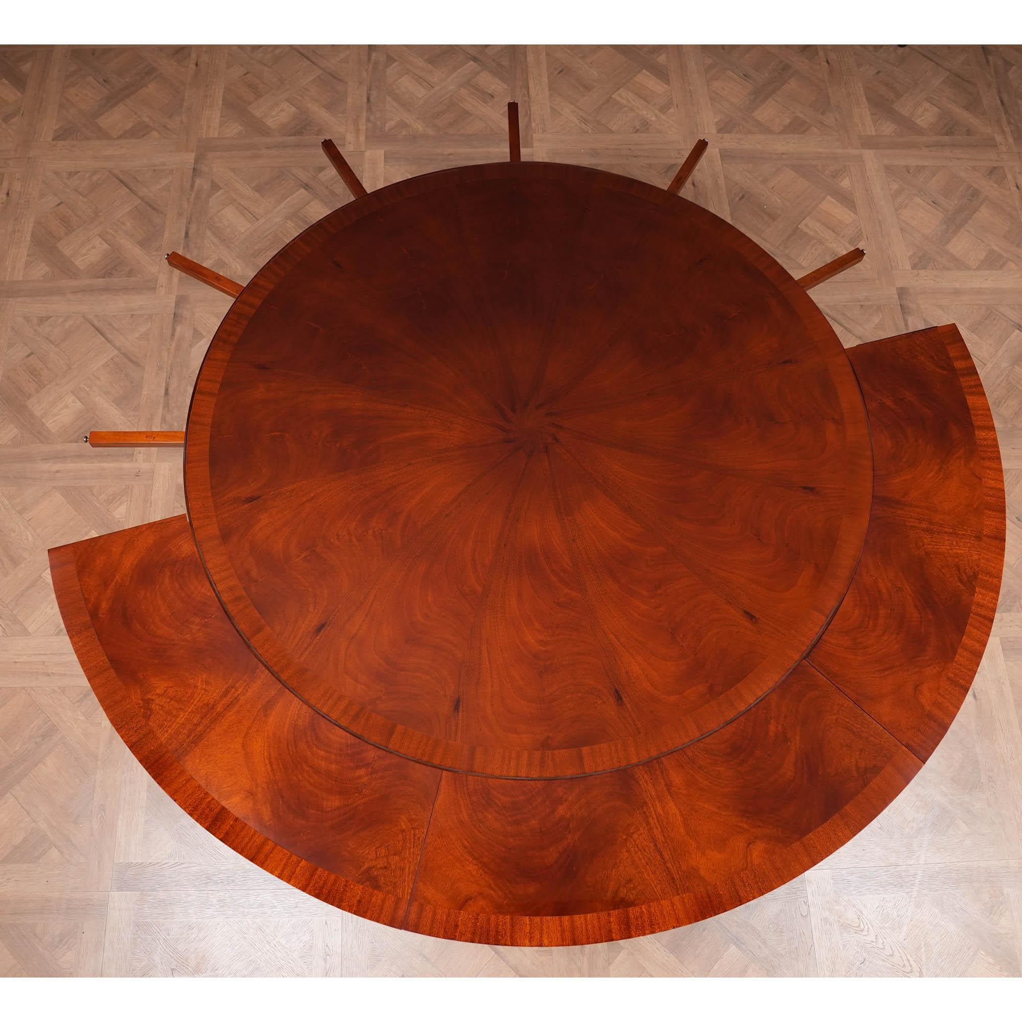 Une table de salle à manger ronde de 60 pouces produite avec un champ d'acajou figuré de haute qualité et des bandes de sapelli qui créent un contraste subtil mais intéressant dans le motif du plateau. Le plateau est entouré de six feuilles qui