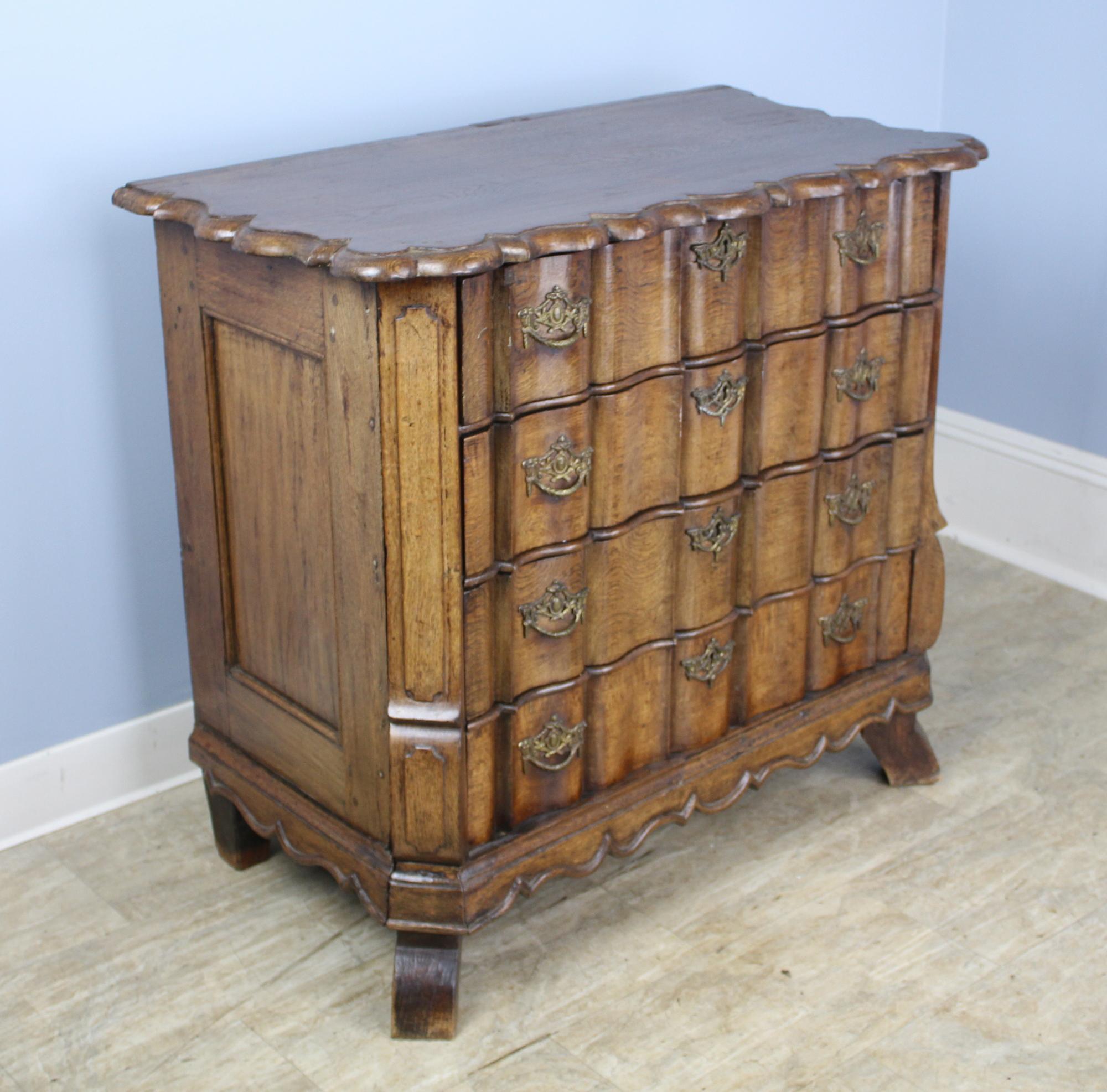 A glowing Dutch oak chest, with serpentine drawers and original brasses, circa 1780. Classic scalloped top and apron, plus splayed feet complete the look. Drawers are clean and slide very easily for a piece of this age. Elegant and imposing.