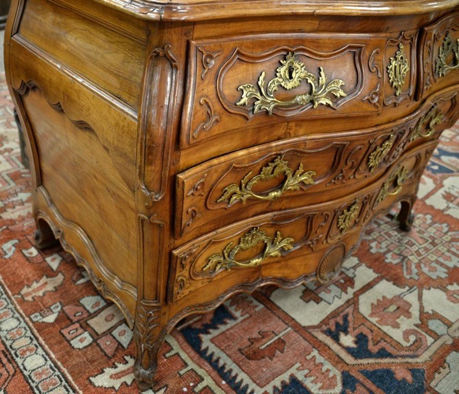 Period bombe walnut commode, Louis XV provincial

Amazing condition and patina. Two over two drawers with molded carved Cartouche fronts. Original feet. Middle secret drawer. Exceptional parquetry top with inlaid symbol in centre. Mortise and