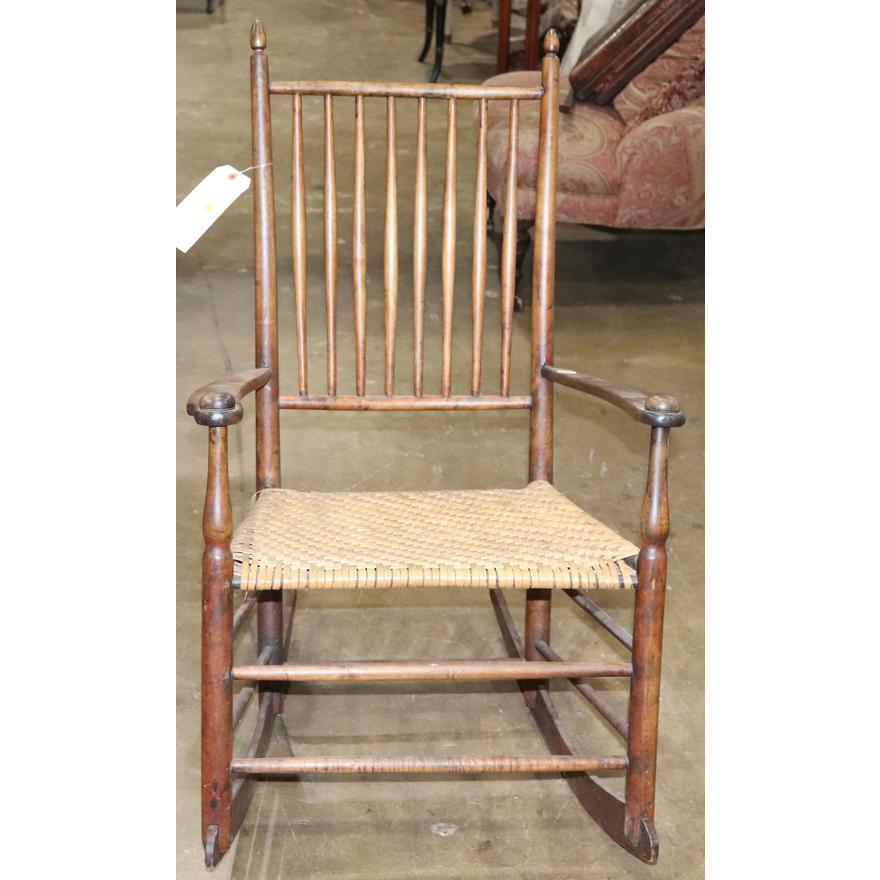 Antique period American Colonial Shaker rocking chair retaining an early rush seat and period rails. Hand whittled spindles, posts and rungs.