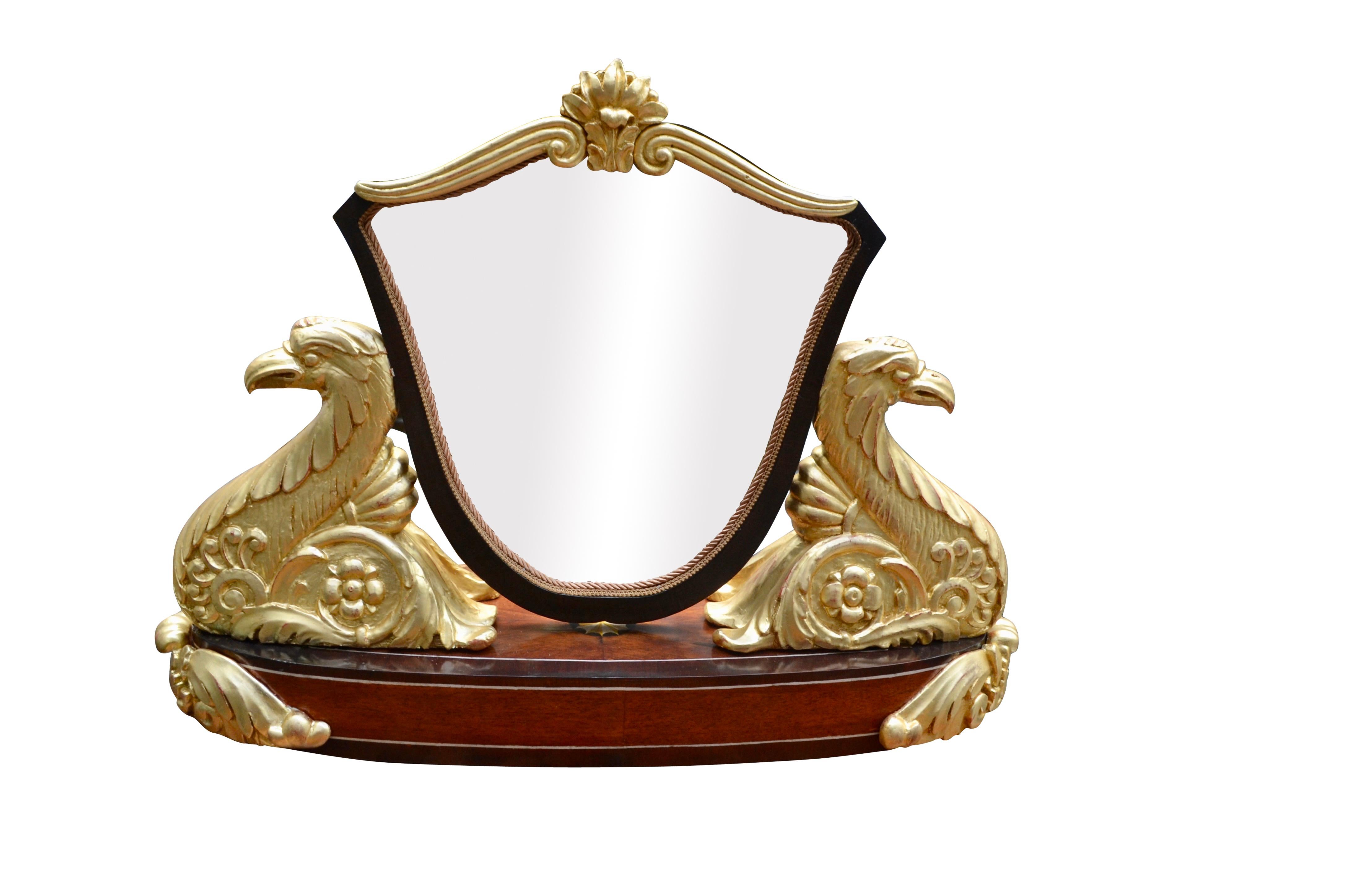 A very handsome and unusual table top dressing mirror likely made in Austria in the early to mid 19thC. The shield shaped mirror has a gilded cartouche on the top with the mirror held in place by large carved and gilded eagle/swans on each side of
