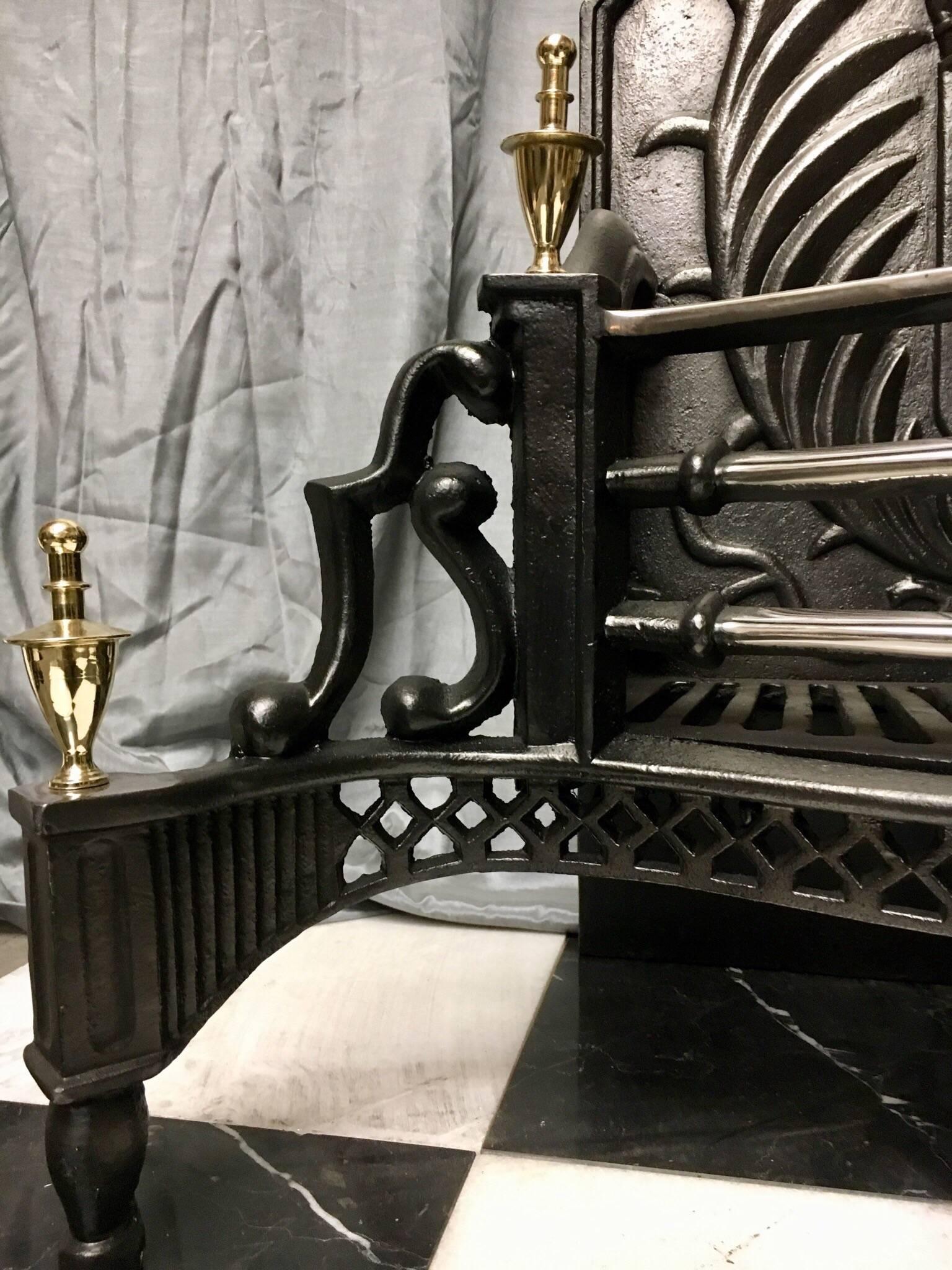 A substantial period cast iron and brass Victorian style fire grate basket, with a large shaped back with castings of a crown and shield with stylised fleur-de-lis flanked by leaf side supporters, shaped side panels connect a four bar polished grate