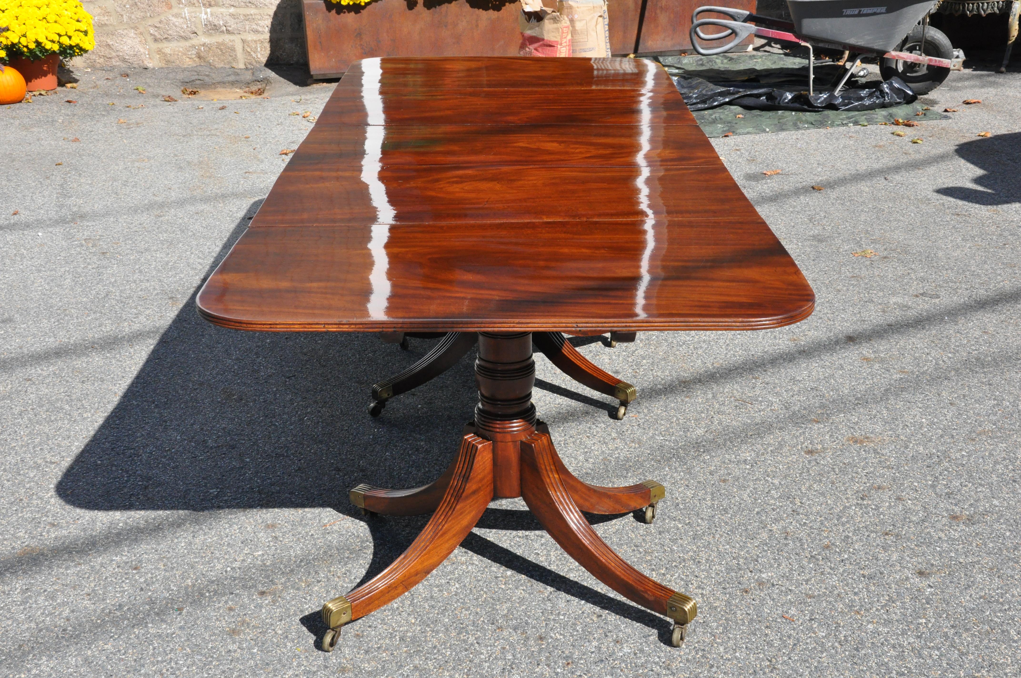 Period American or English three pedestal dining table with two additional leaves.
-- Original and Magnificent figuring of the mahogany boards. This remarkable table exists as a drop-leaf central section with two original end sections. The table