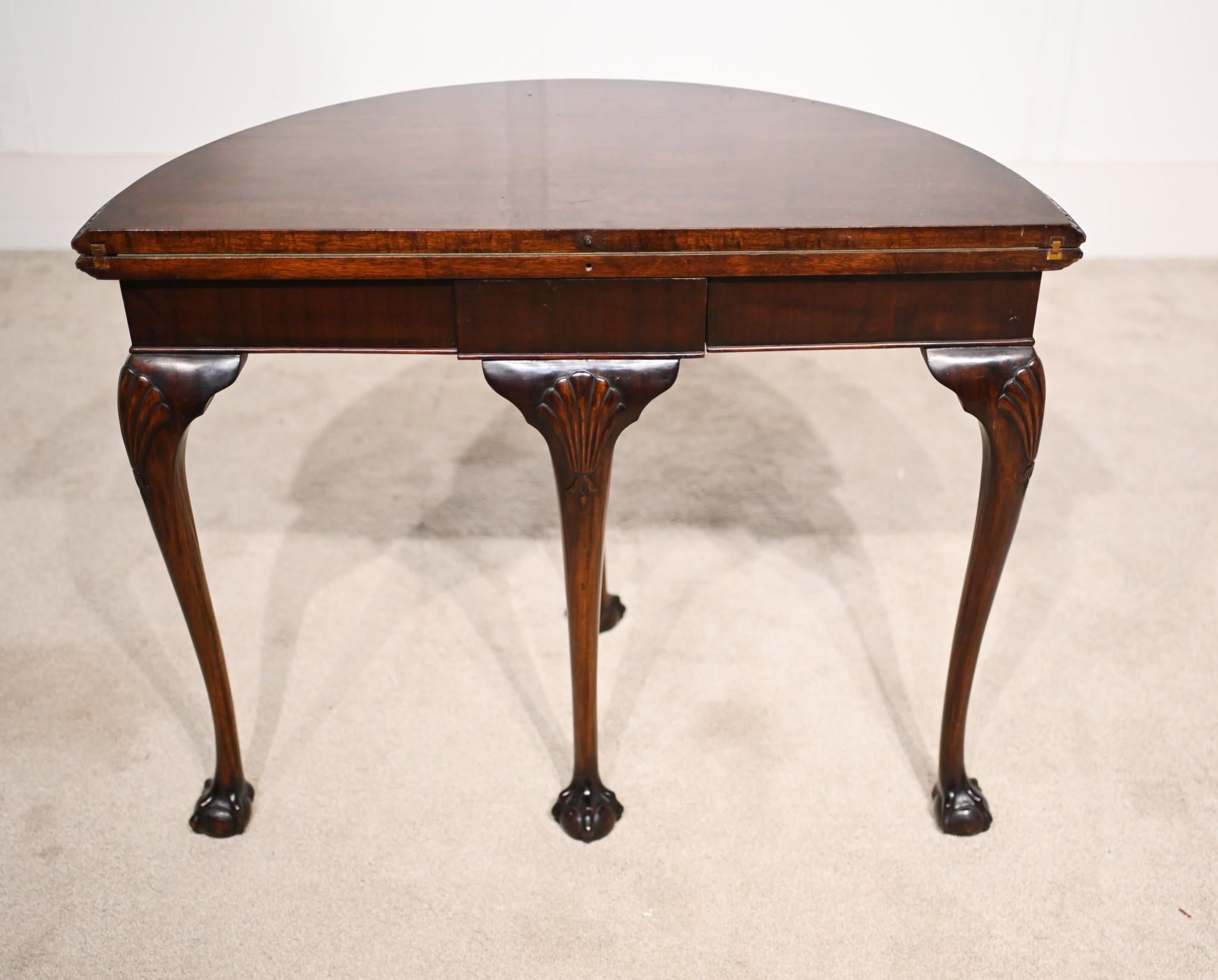 Table à cartes épurée et élégante de style Elegardien en acajou
Demi-ronde - forme demi-lune - avec pieds en boule et griffes
Le couvercle s'ouvre pour révéler une surface de jeu tapissée de beige vert.
Acheté dans une maison privée de Holland Park