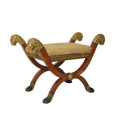 Banco Imperio de época con cuatro cabezas de león talladas y doradas a la parcela