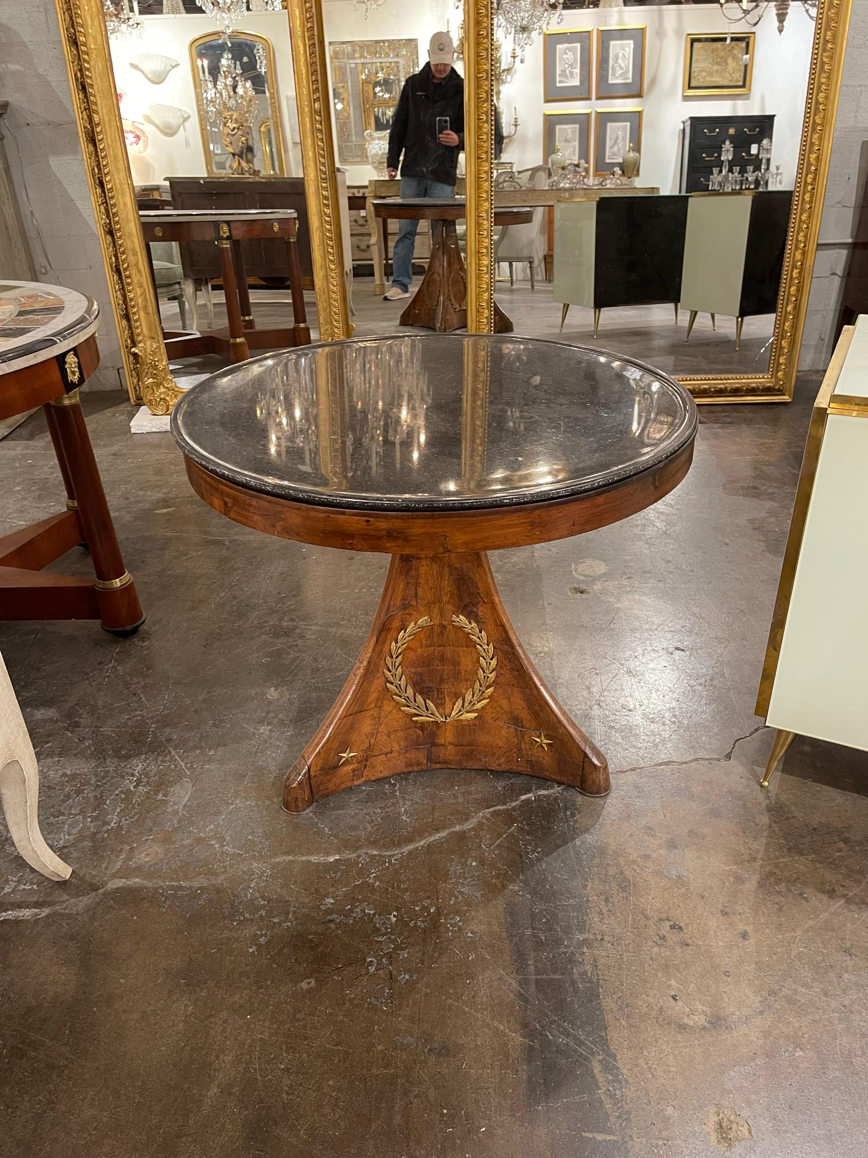 Very fine early 19th century Period Empire mahogany centre table. The circular top with a superb Belgian black marble. The tri-concave shaped pedestal base adorned with exquisite gold gilded laurel wreaths and bronze star appointments,

circa 1830.