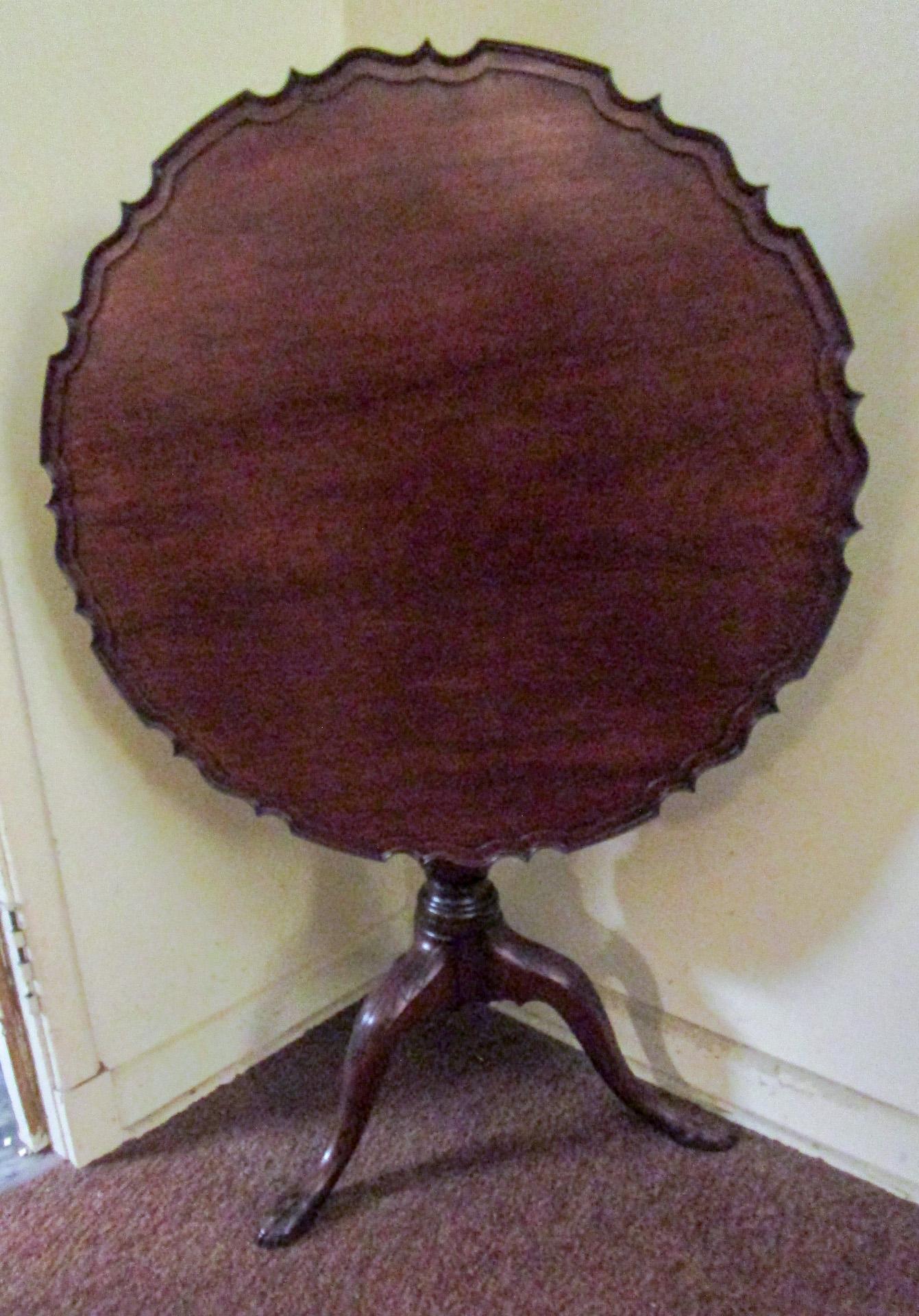This outstanding large size period Chippendale English mahogany tilt-top table features a hand carved piecrust top on a birdcage and leaf carving on the tripod legs. This sturdy table could be used as an extra tea table tucked away tilted up or as a