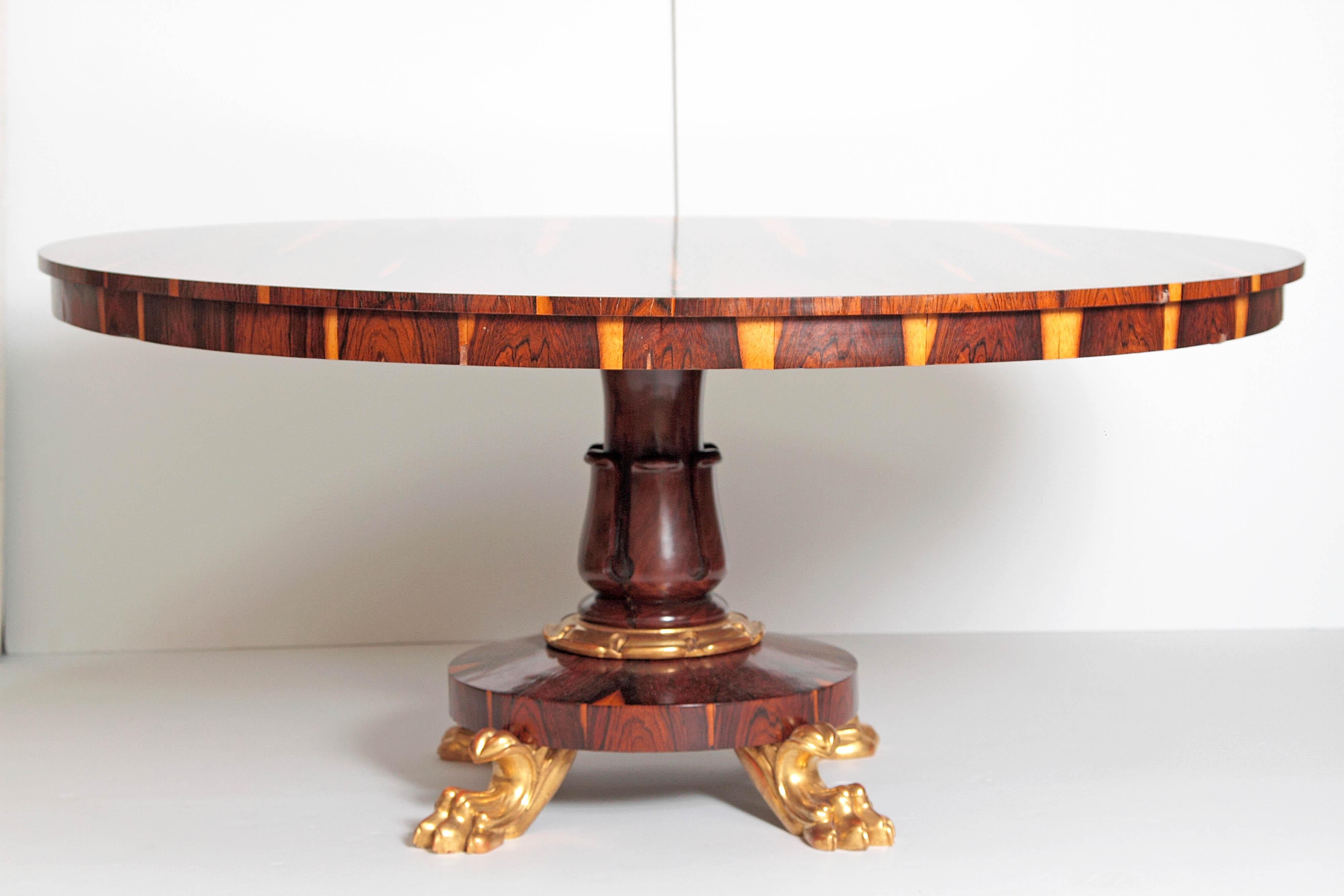 An impressive looking large Regency center table of calamander wood. A beautifully patterned top with carved pedestal base with gilt band above round base with four gilt lion paw feet. Early 19th century, circa 1820, England.