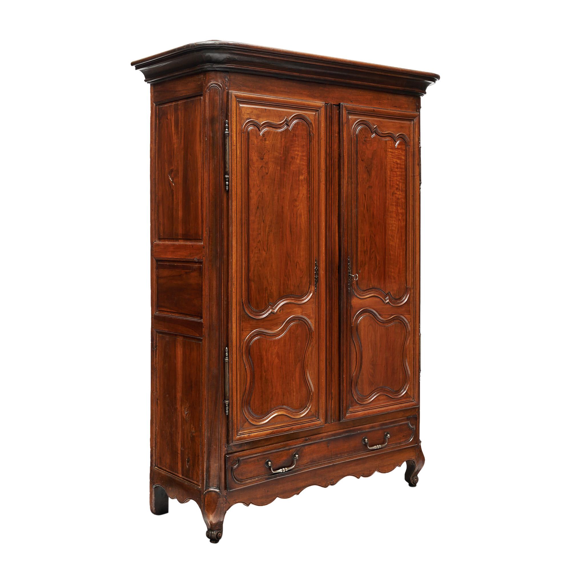 French armoire in the Louis XV style from the 18th century. This piece is made of solid wood construction, primarily walnut. It has been finished with hand rubbed bees wax and Carnauba wax. The carved doors having original, hand forged  working