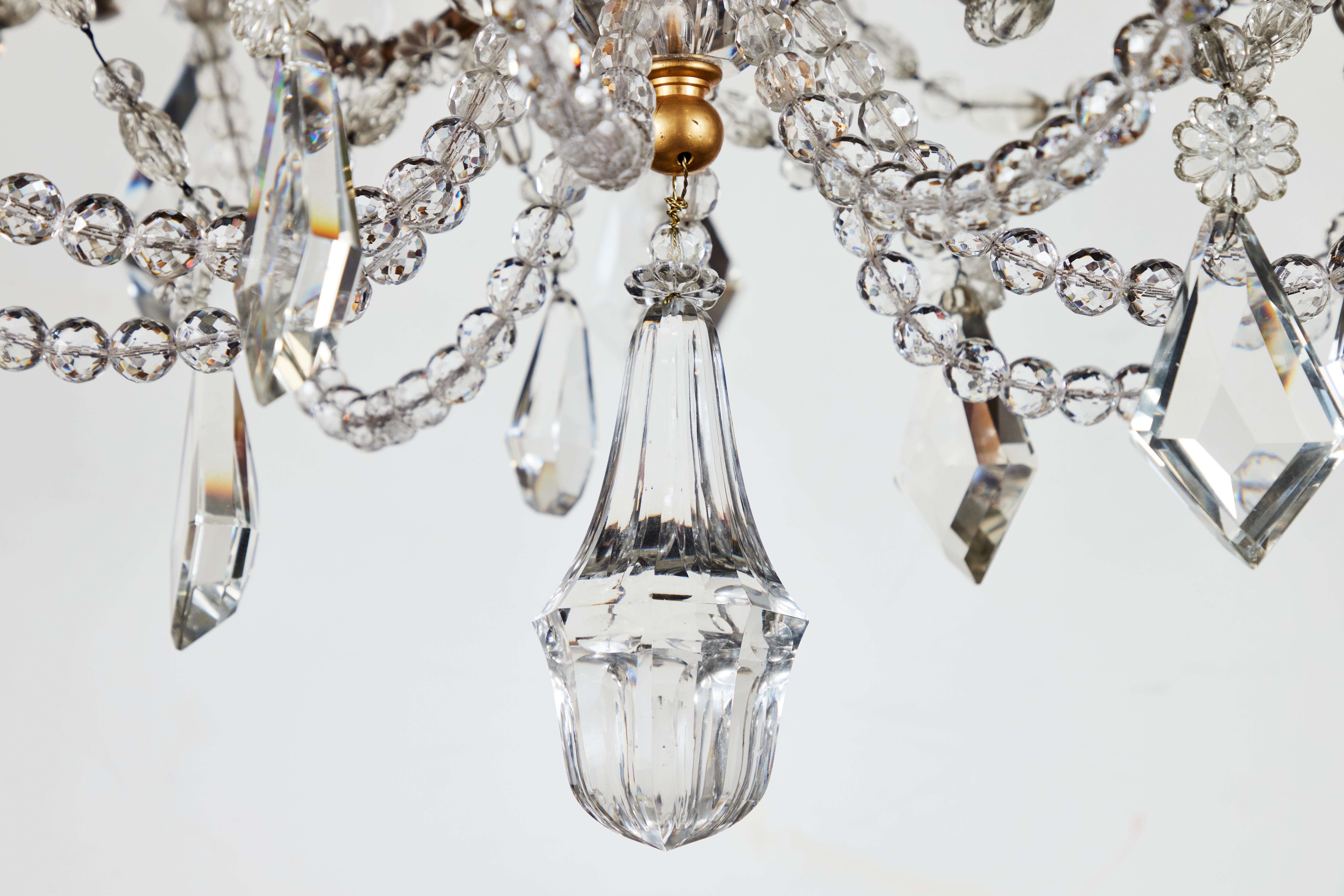 A superb, early 1800’s, French, nine-arm, gilt bronze chandelier dripping in generous amounts of cut crystal. The whole embellished with crystal towers and drops while the center features an extraoridnary series of chains with encased, marquis
