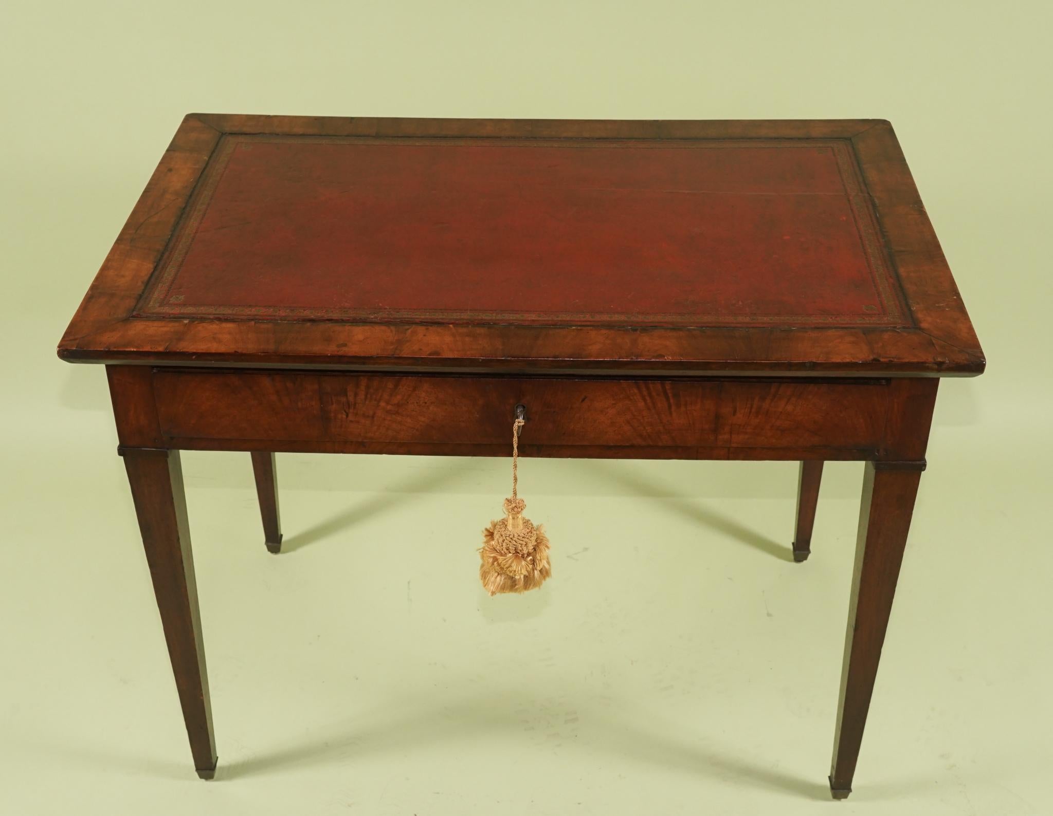 Cette belle table d'écriture d'époque a été construite en France entre 1790 et 1800 en riche acajou importé. Les bois ont été soigneusement sélectionnés pour créer un motif général de grain flamboyant autour du tablier de la table. Le plateau est