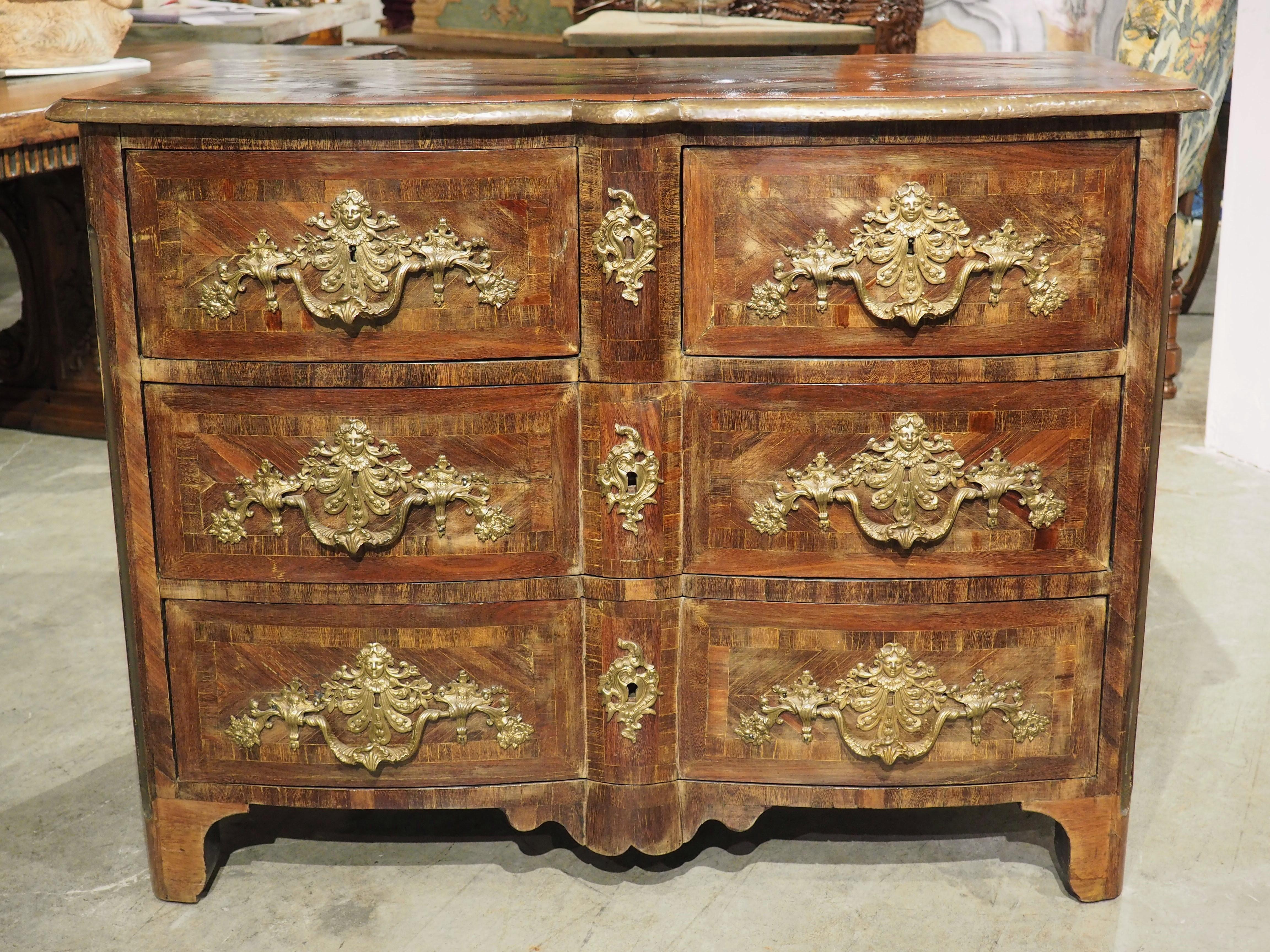 Produced in France, circa 1705, our period Louis XIV commode features rich bronze ornamentation and exceptional parquetry work. Perhaps the most stunning display of the technique is the patterned diamond top, which is surrounded by a quarter round