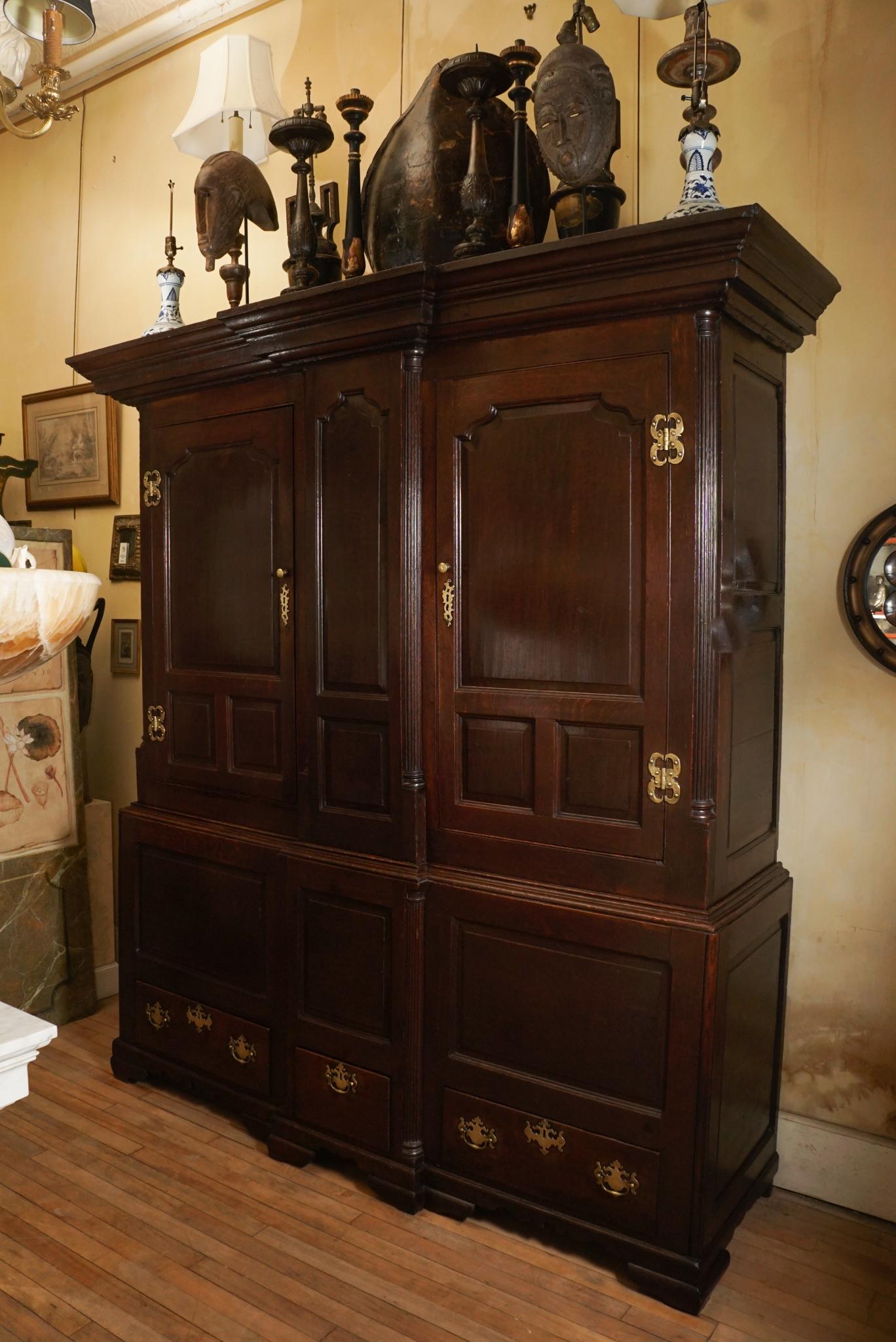 This wonderful old cupboard is crafted of sturdy English oak and was made circa 1740. Retaining its fine old surface, richly waxed and polished, the cabinet is comprised of a large two-door upper section the extends past the door line into the lower