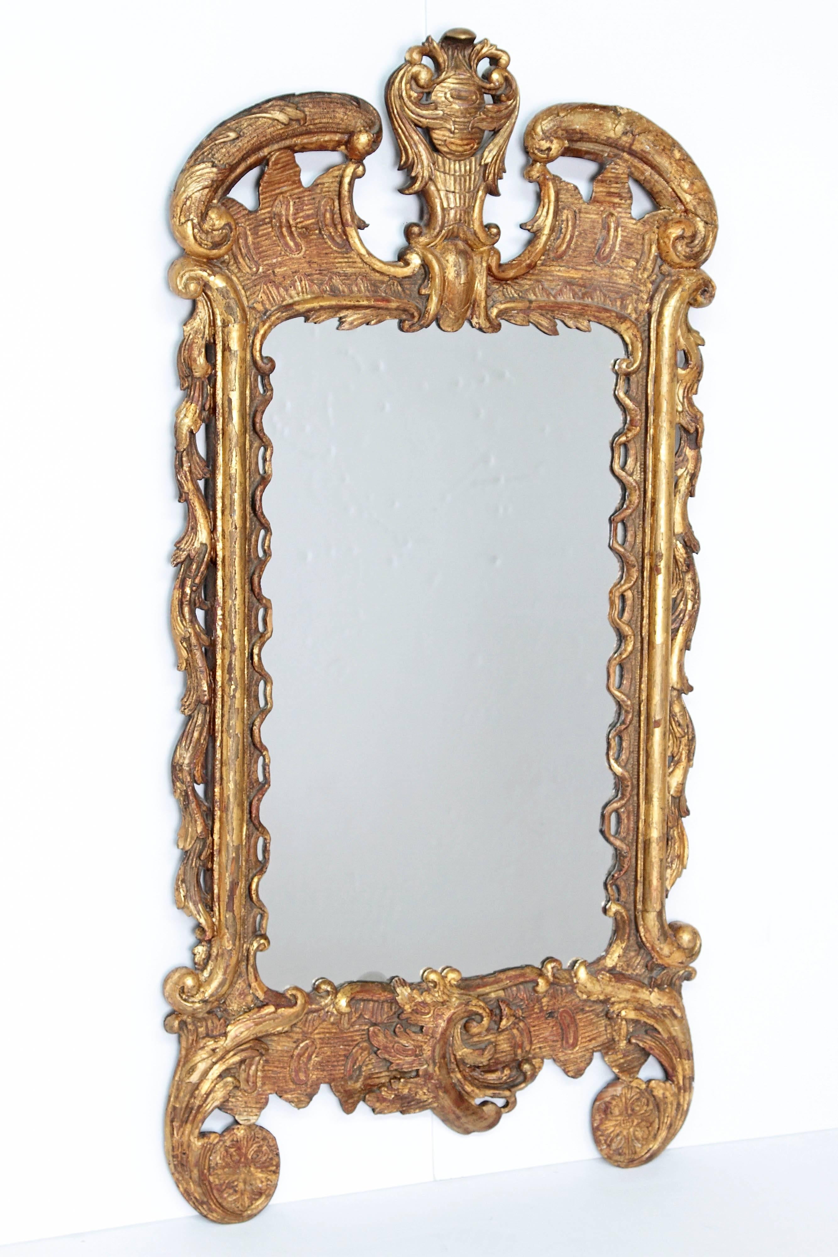 Late 18th-early 19th century George III period giltwood hand-carved pier glass / mirror, high-shouldered curved broken pediment and foliate carved center crest, open fluted wave style curving down interior side of mirror, and acanthus leaf carvings
