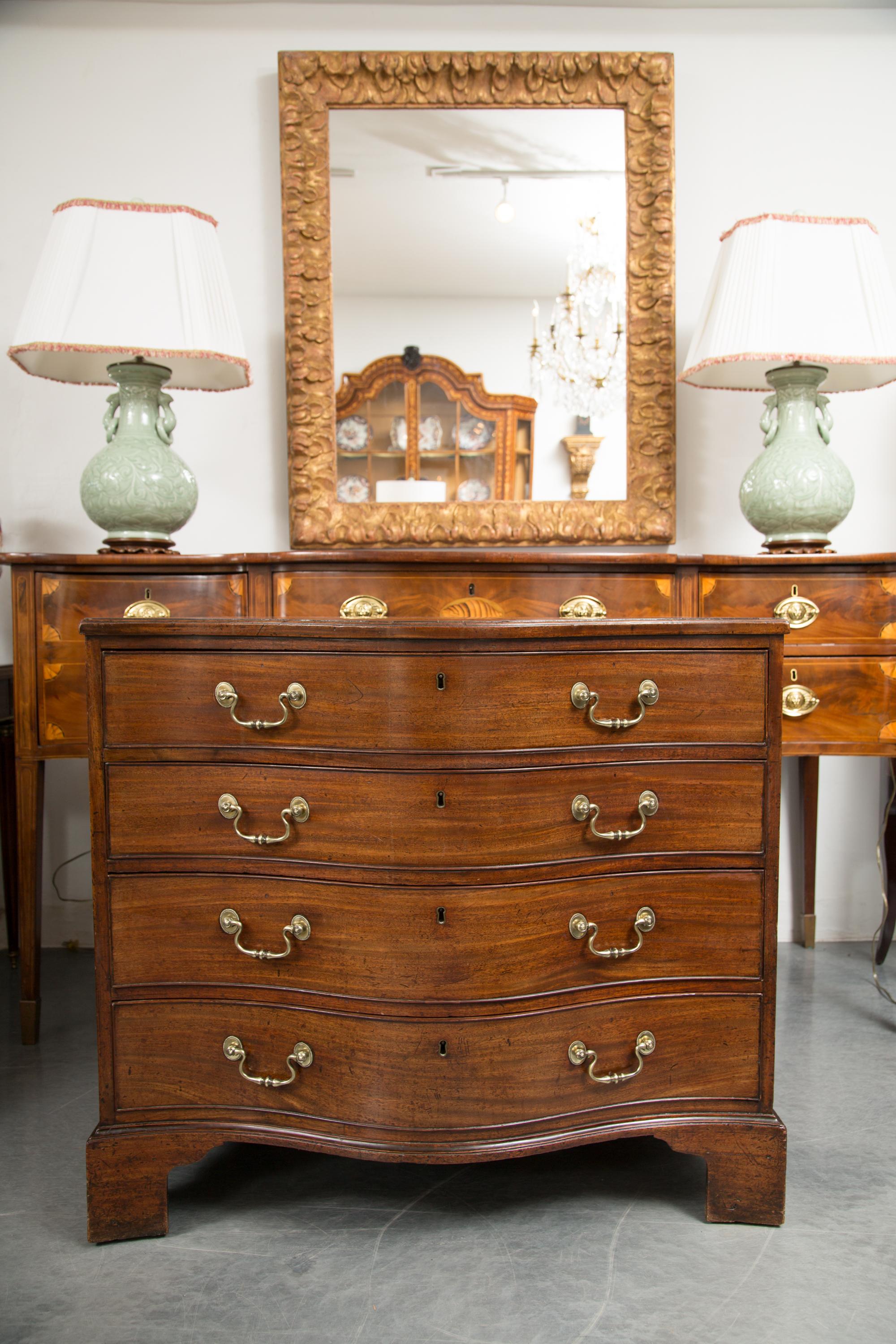 This is a Classic period English mahogany Georgian serpentine chest of drawers. The serpentine top with straight edge in over four long conforming drawers. The chest of drawers is raised on bracket, circa 1790.