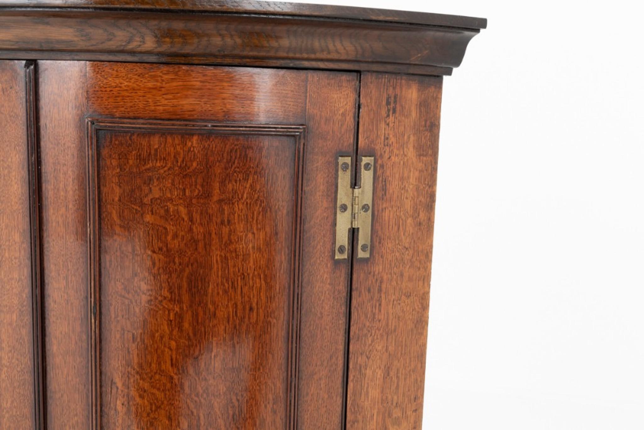 Georgian oak bow corner cupboard.
Circa 1800
This corner cupboard features paneled doors with ''h'' hinges.
The doors open to reveal 3 interior shelves.

Presented in good condition