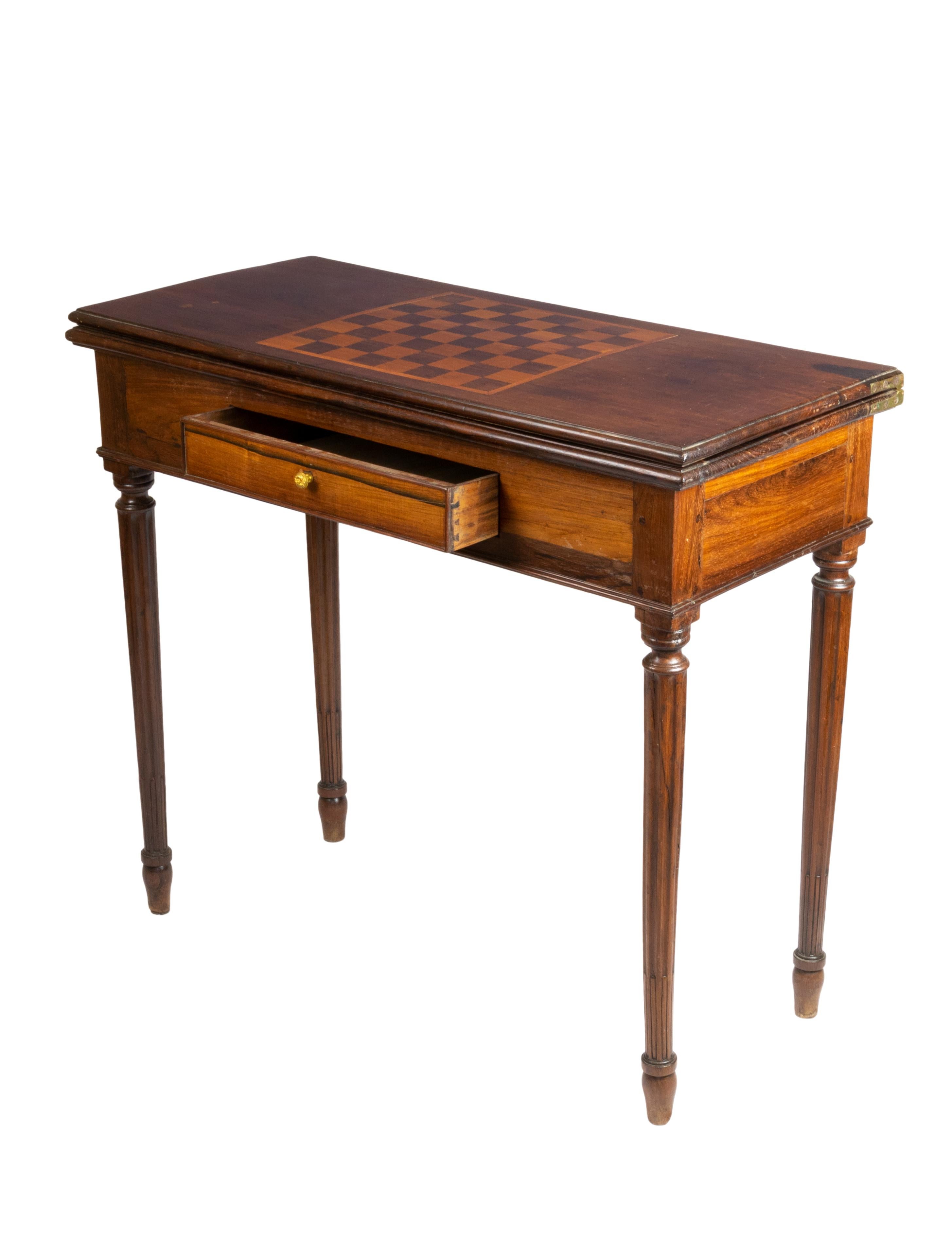 A very exquisite George III period card table in excellent original condition. A leg opens out to hold the playing surface with a green felt., a chess marquetry board and a center drawer.

Height 80 cm
Open 91 x 83.5 cm
Closed: 91 x 41.5 cm